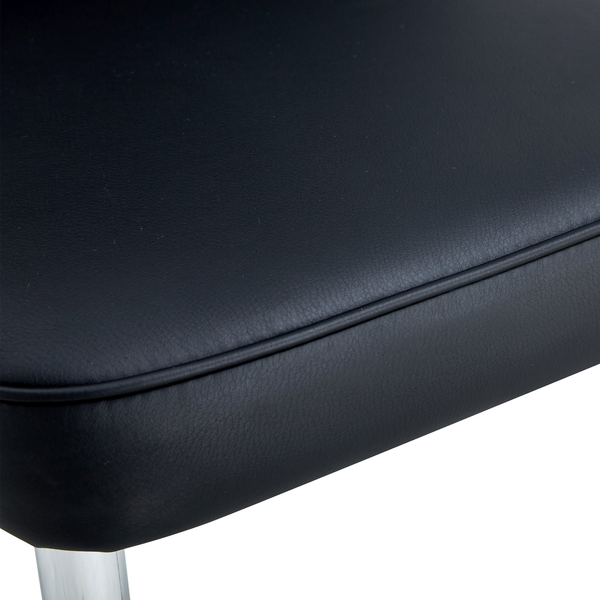 Closeup of black faux leather seat with piped edge detail