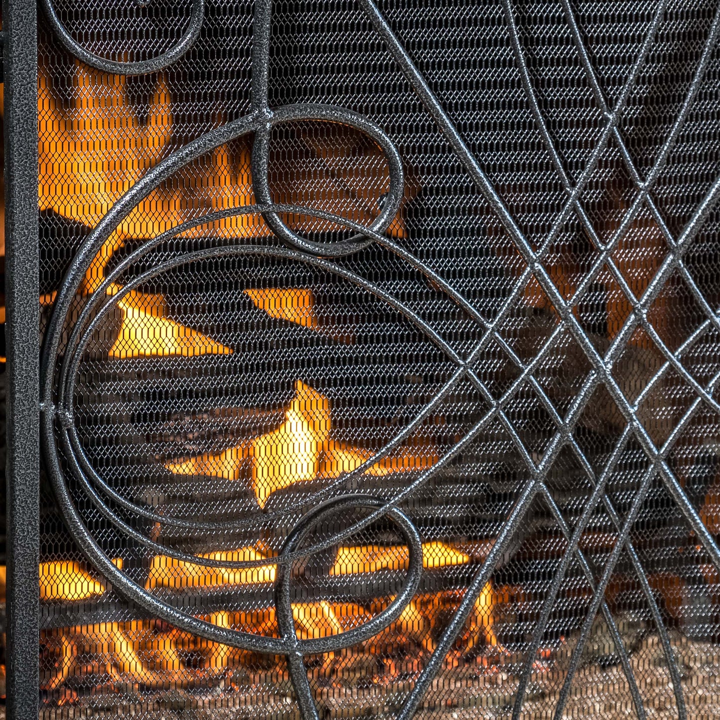 Ornate metal fireplace screen with flickering flames behind mesh