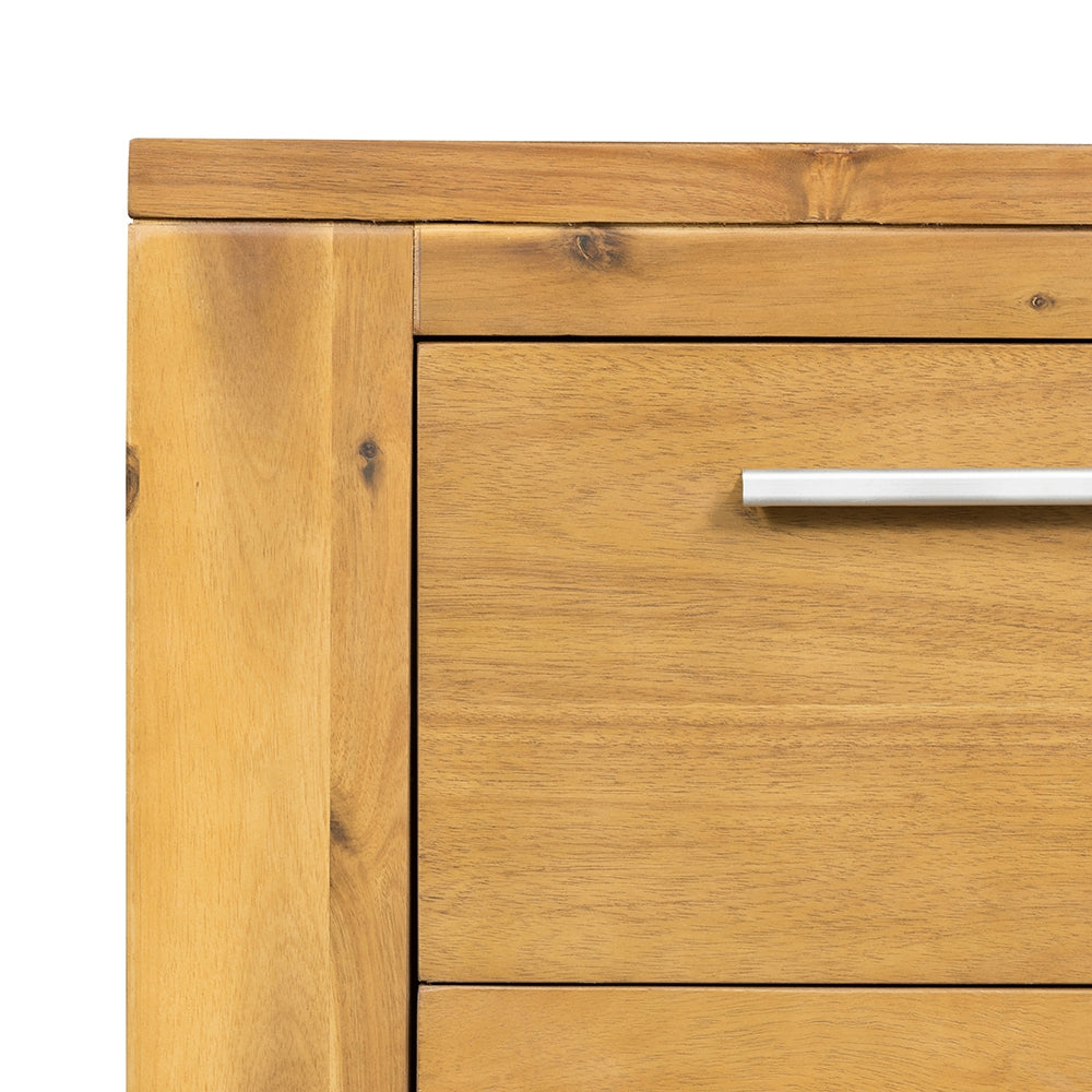 Closeup of a natural wood dresser drawer with a silver handle