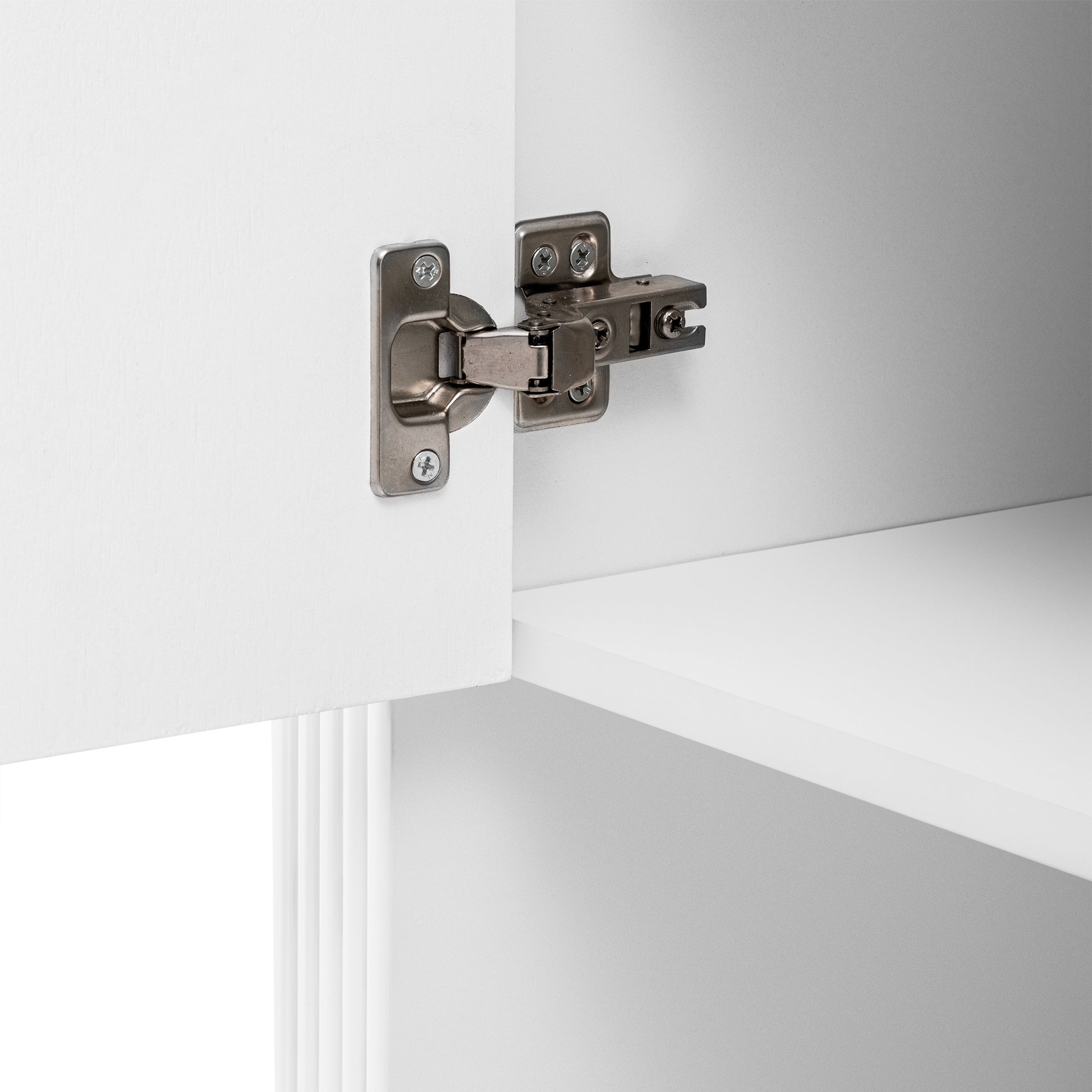 Closeup of brushed nickel cabinet hinge attached to white cabinet door