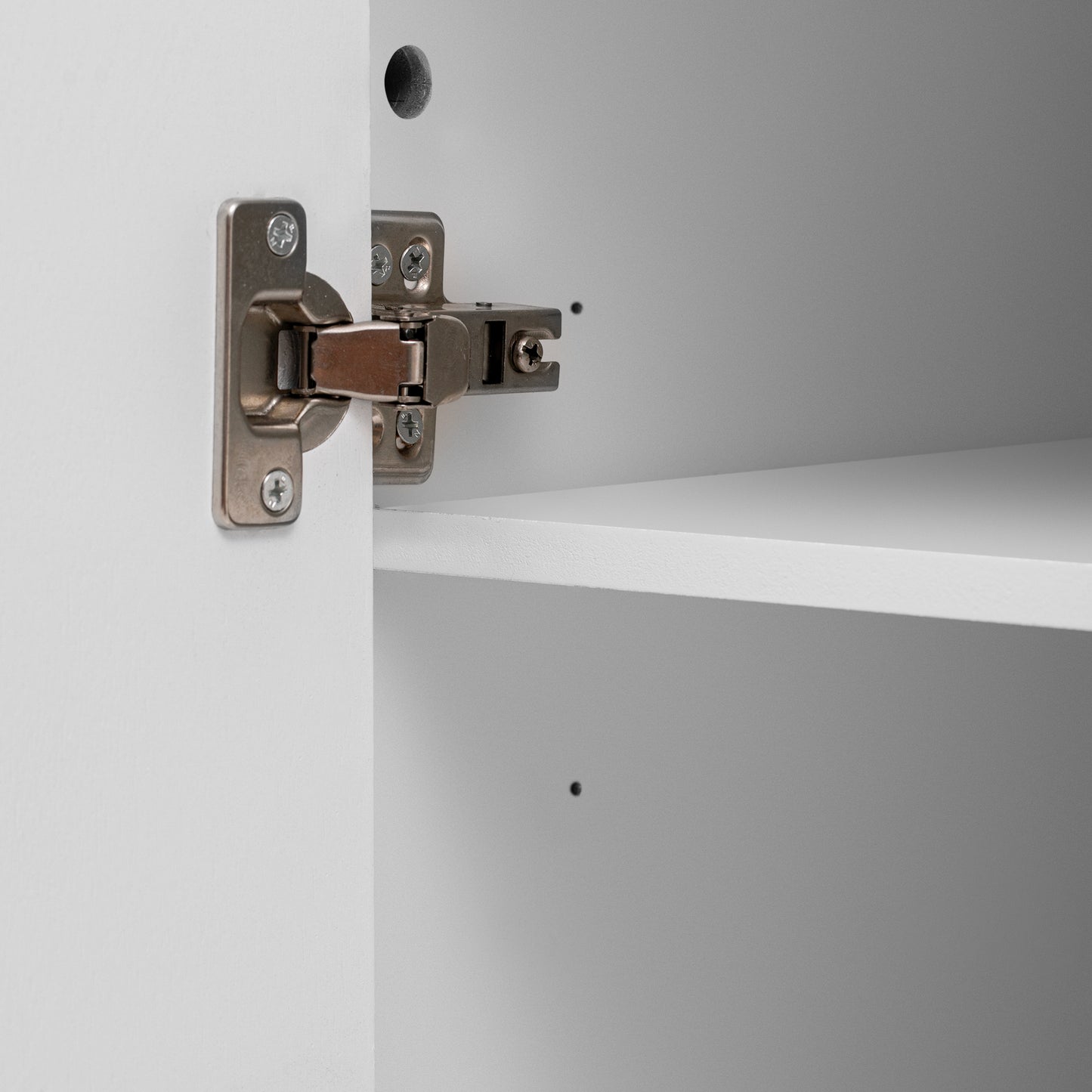 Closeup of a brushed nickel cabinet hinge with silver screws
