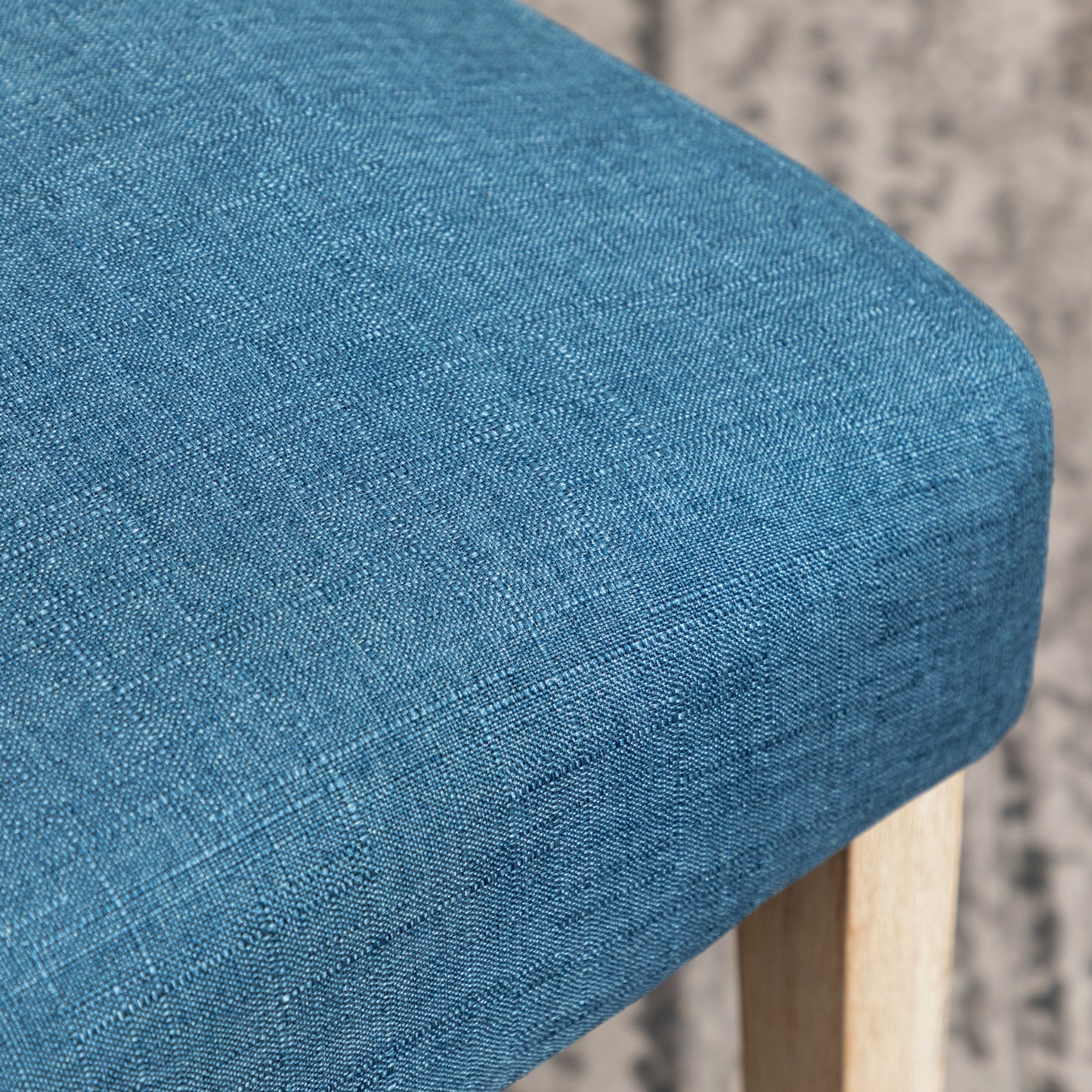 Closeup of a textured blue fabric seat with a light wood frame visible