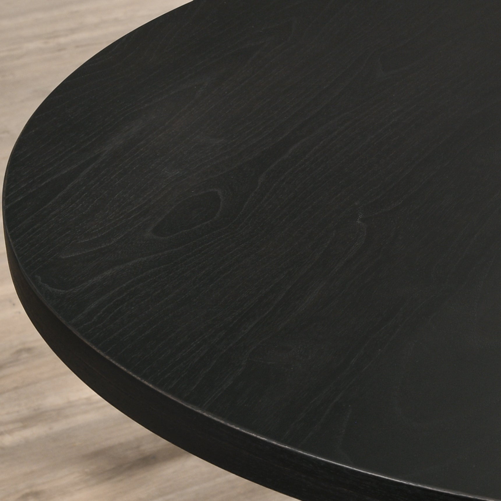 Closeup of a black round wood table surface with visible grain texture