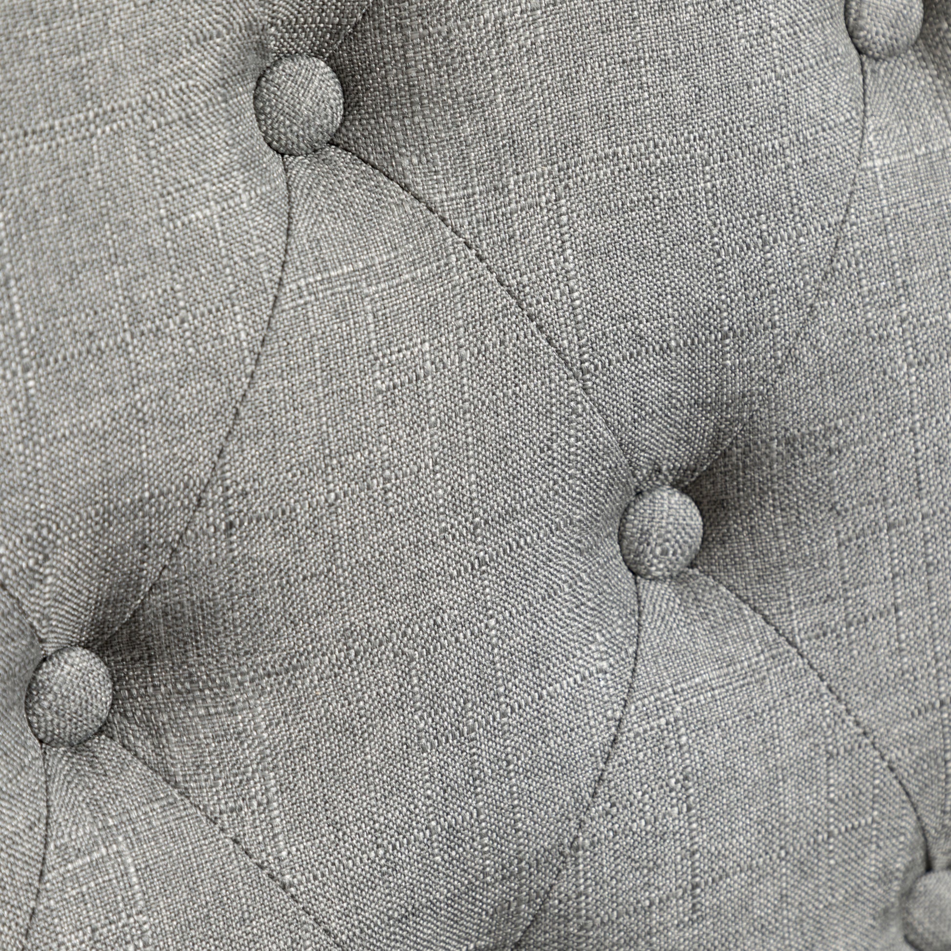 Closeup of grey textured fabric with diamond tufting detail
