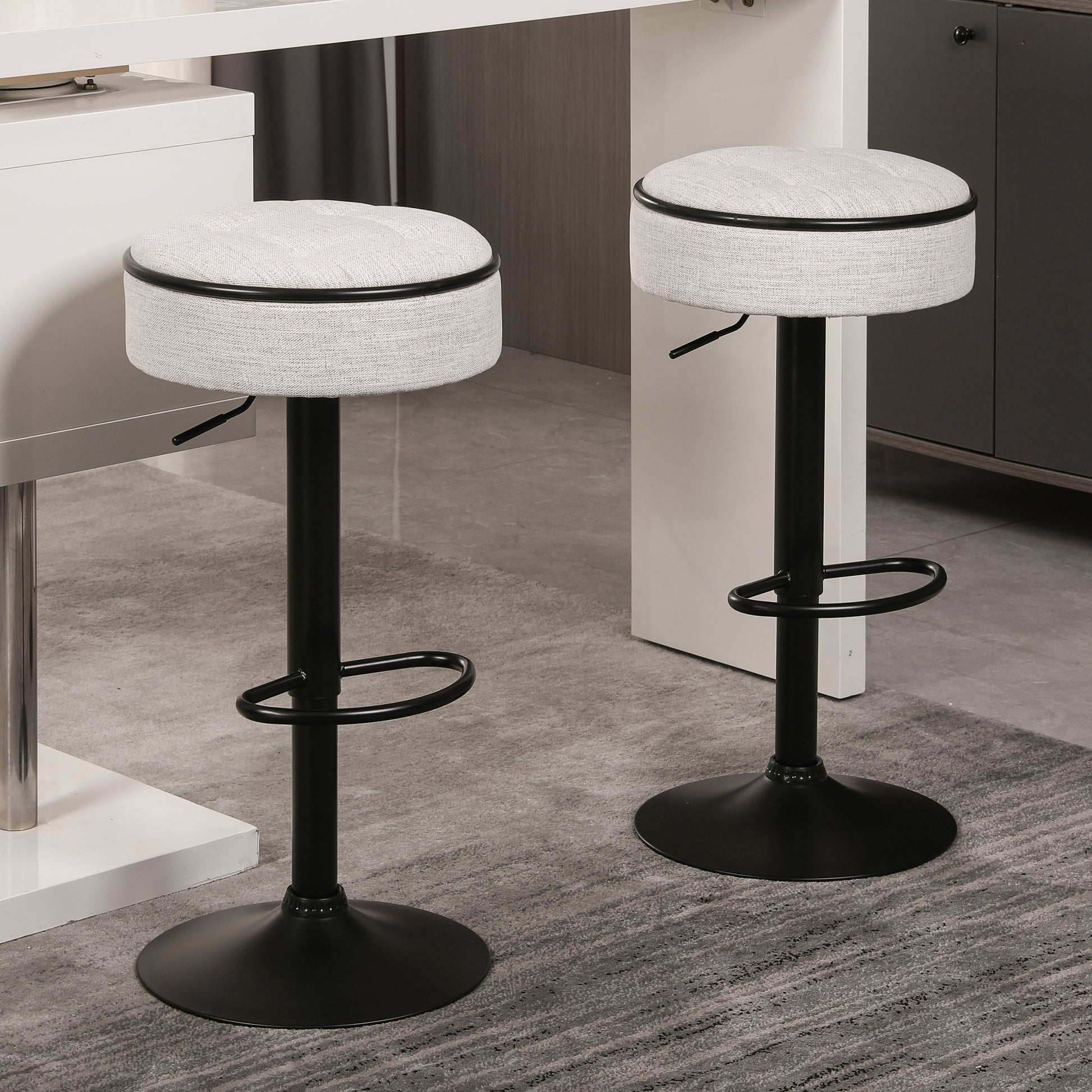 Gray upholstered adjustable height bar stool with black metal base and footrest