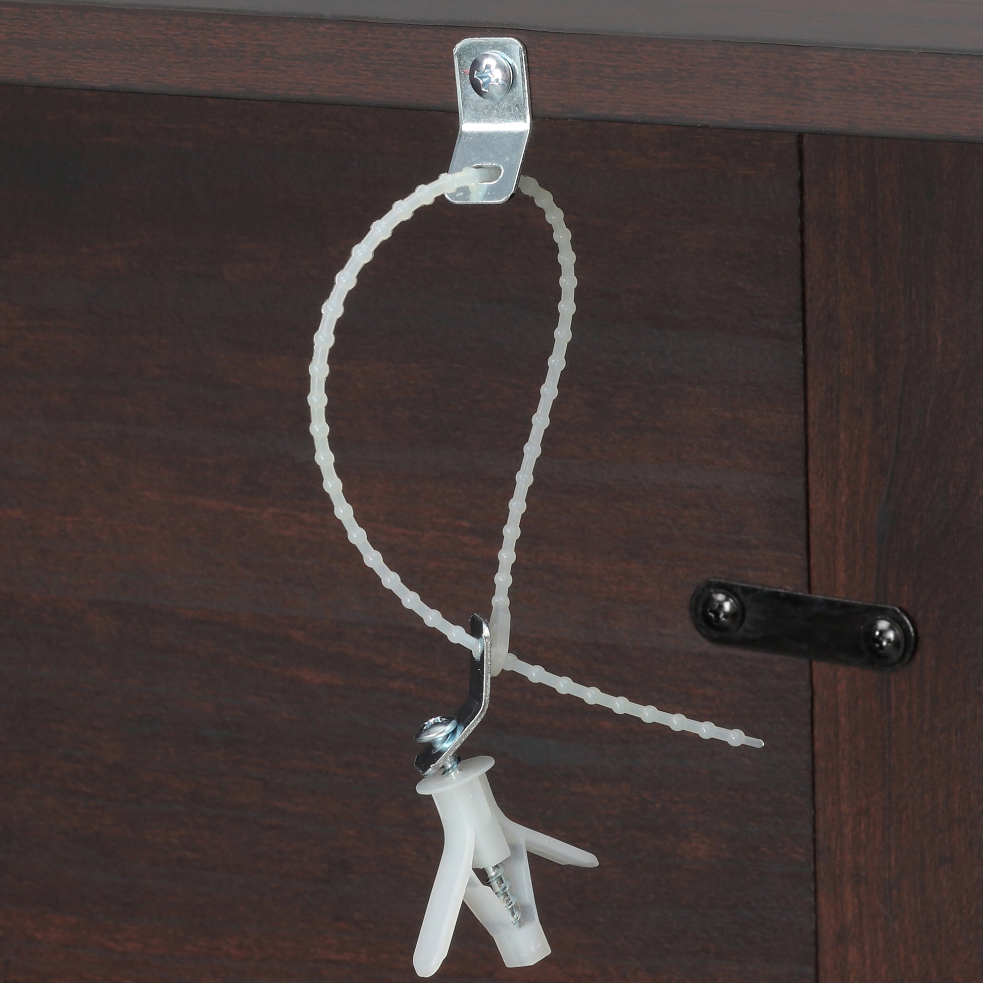 White plastic beaded cable tie securing a toggle bolt anchor to dark wood furniture
