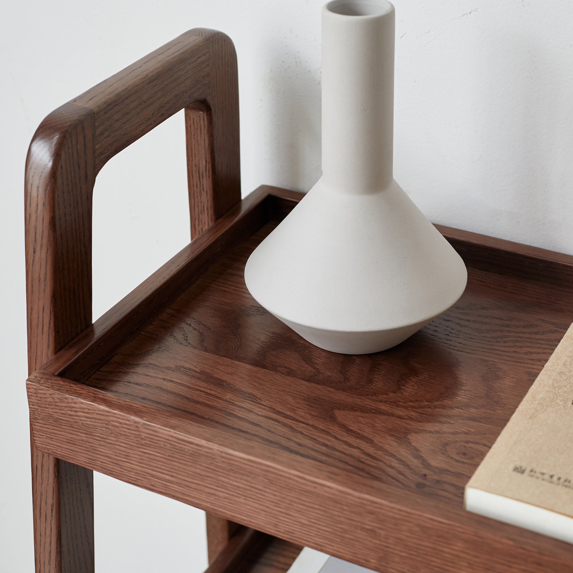 Dark wood side table with a modern ceramic vase and book