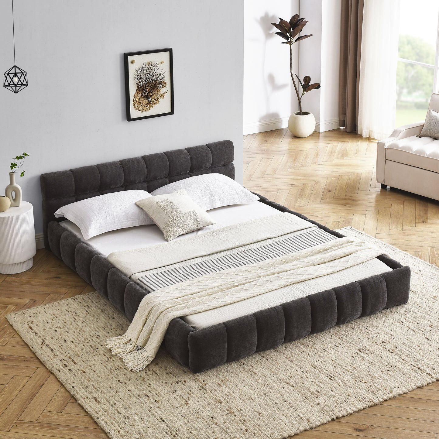 Dark gray tufted platform bed frame with white linens and throws