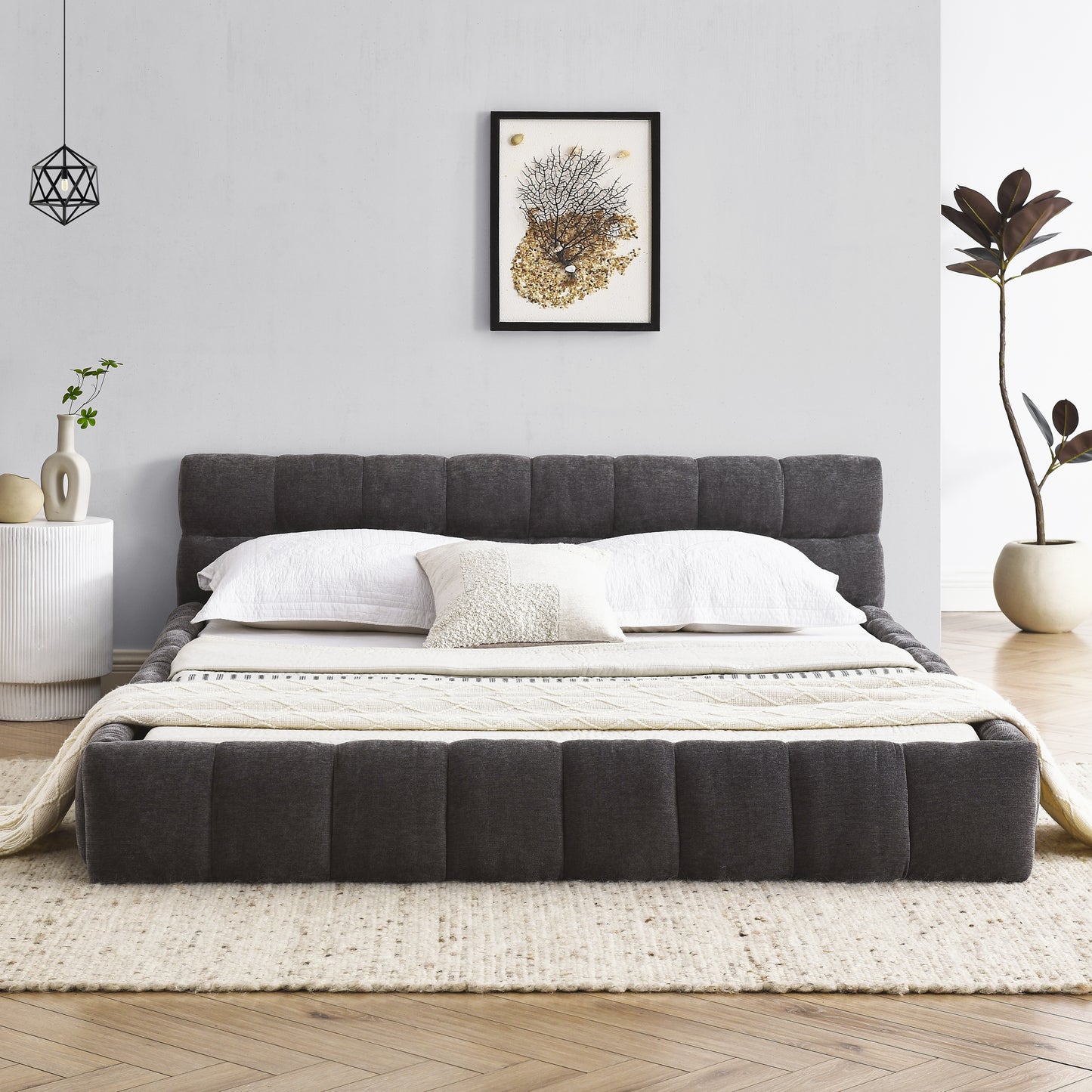 Dark grey upholstered platform bed with quilted headboard and white linens