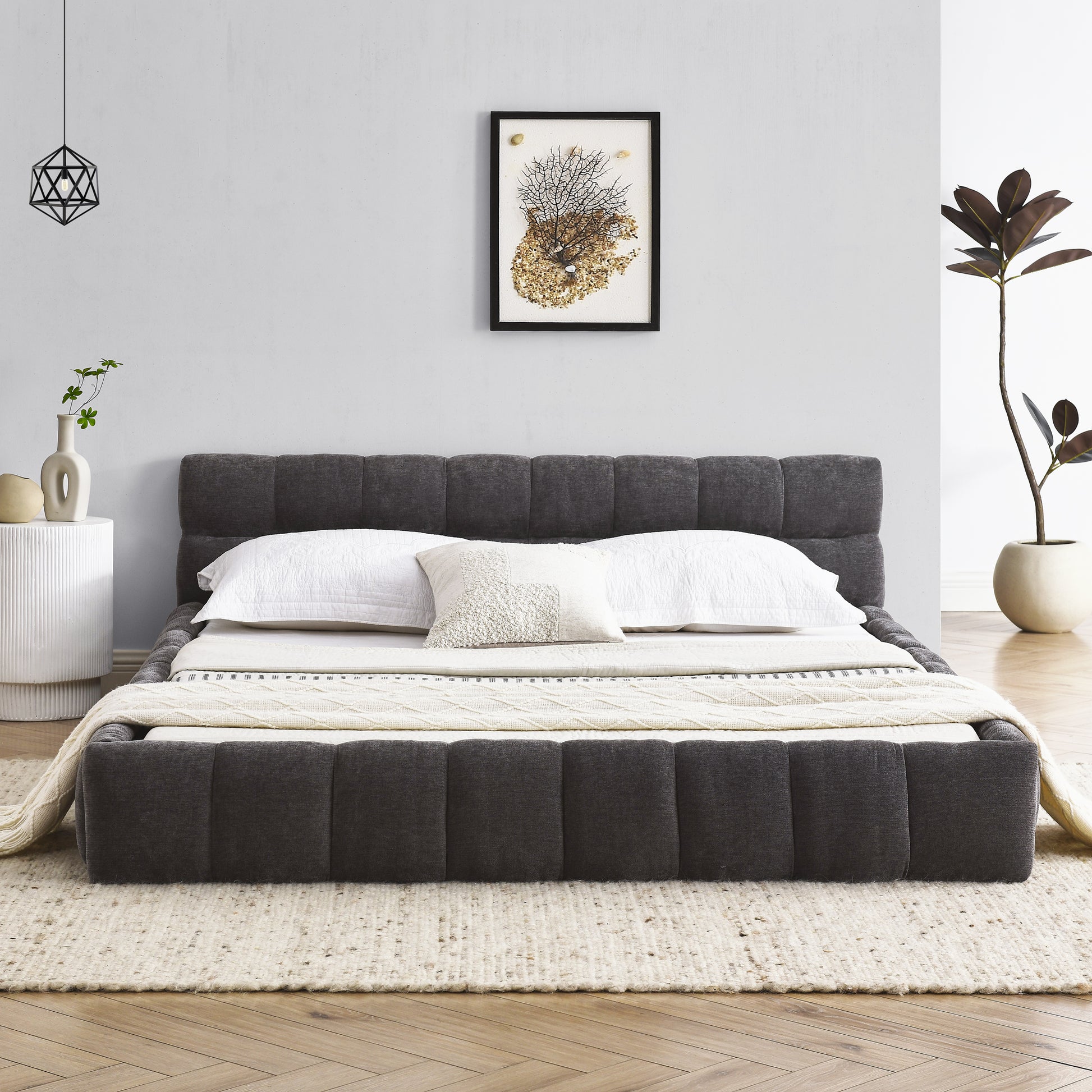 Dark grey upholstered platform bed with quilted headboard and white linens