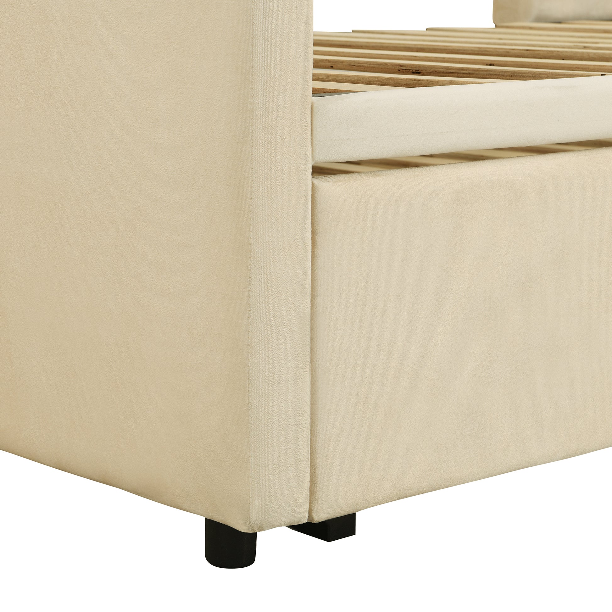 Closeup of plush beige upholstered bed frame corner showing wooden slats and black legs