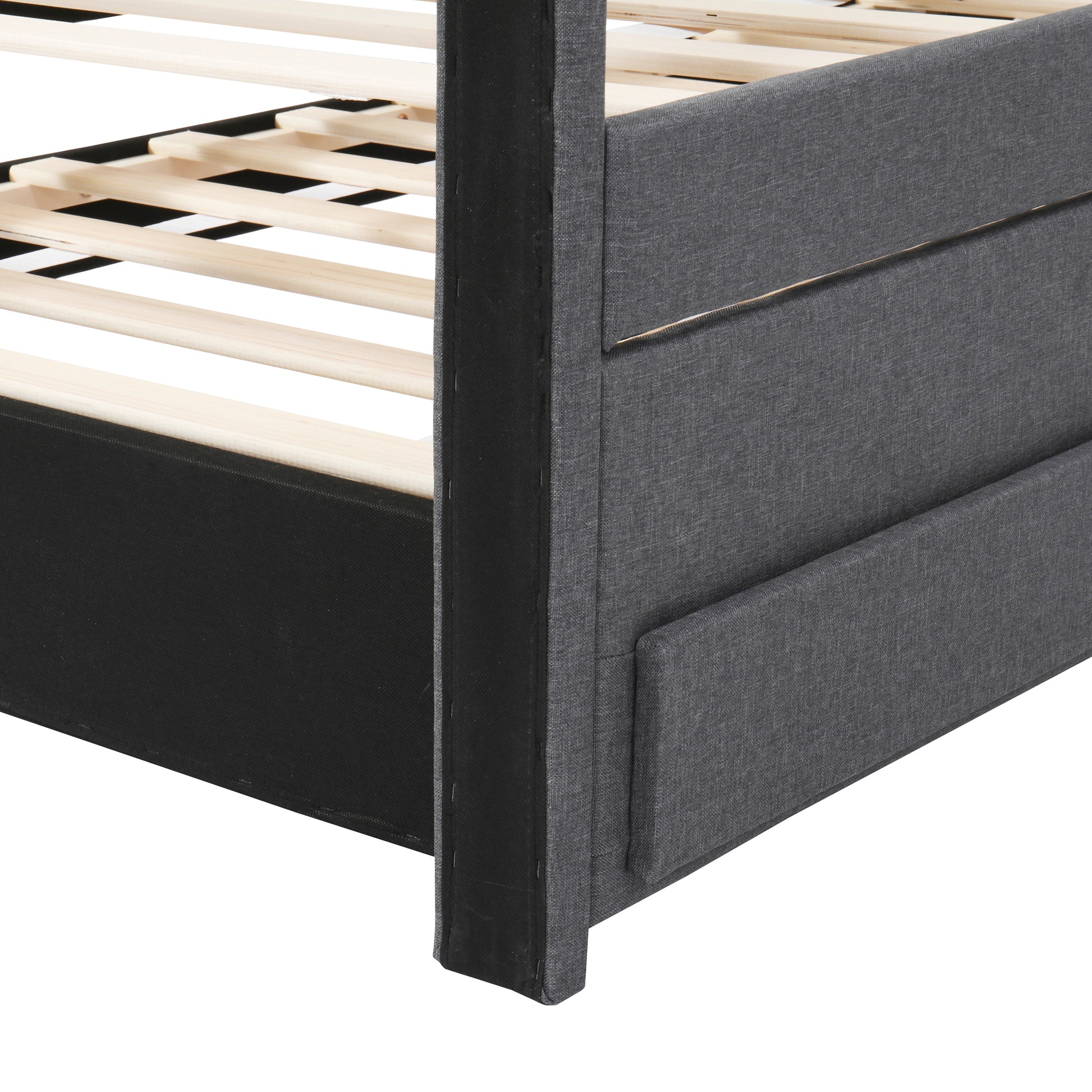 Closeup of a charcoal grey upholstered bed frame with wooden slats