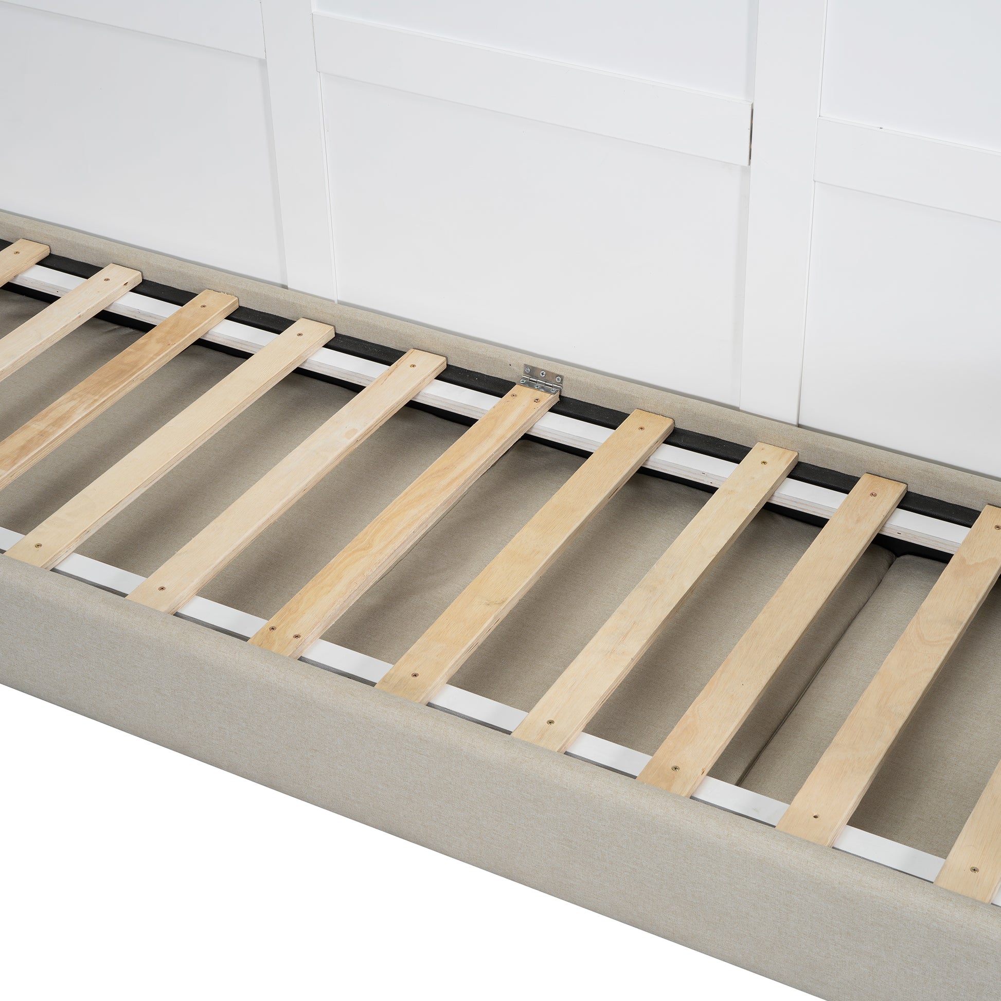 Closeup of a beige upholstered bed frame with a wooden slatted base and white headboard