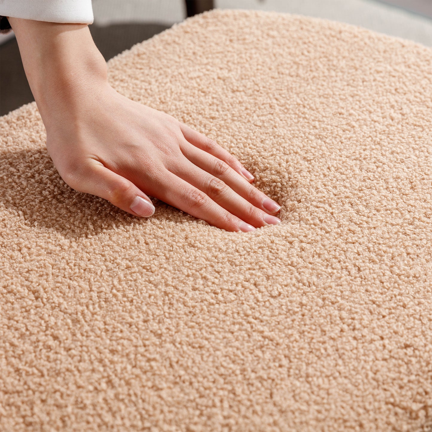 Closeup of a hand pressing into a plush beige teddy fabric throw