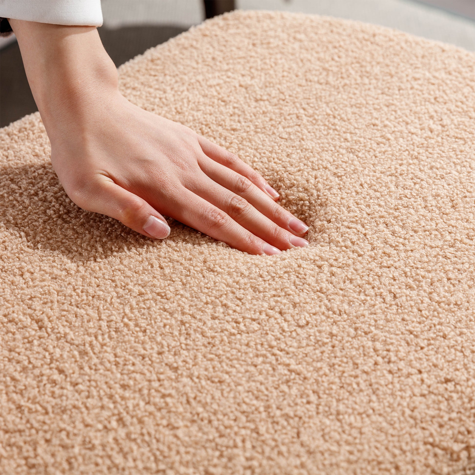 Closeup of a hand pressing into a plush beige teddy fabric throw