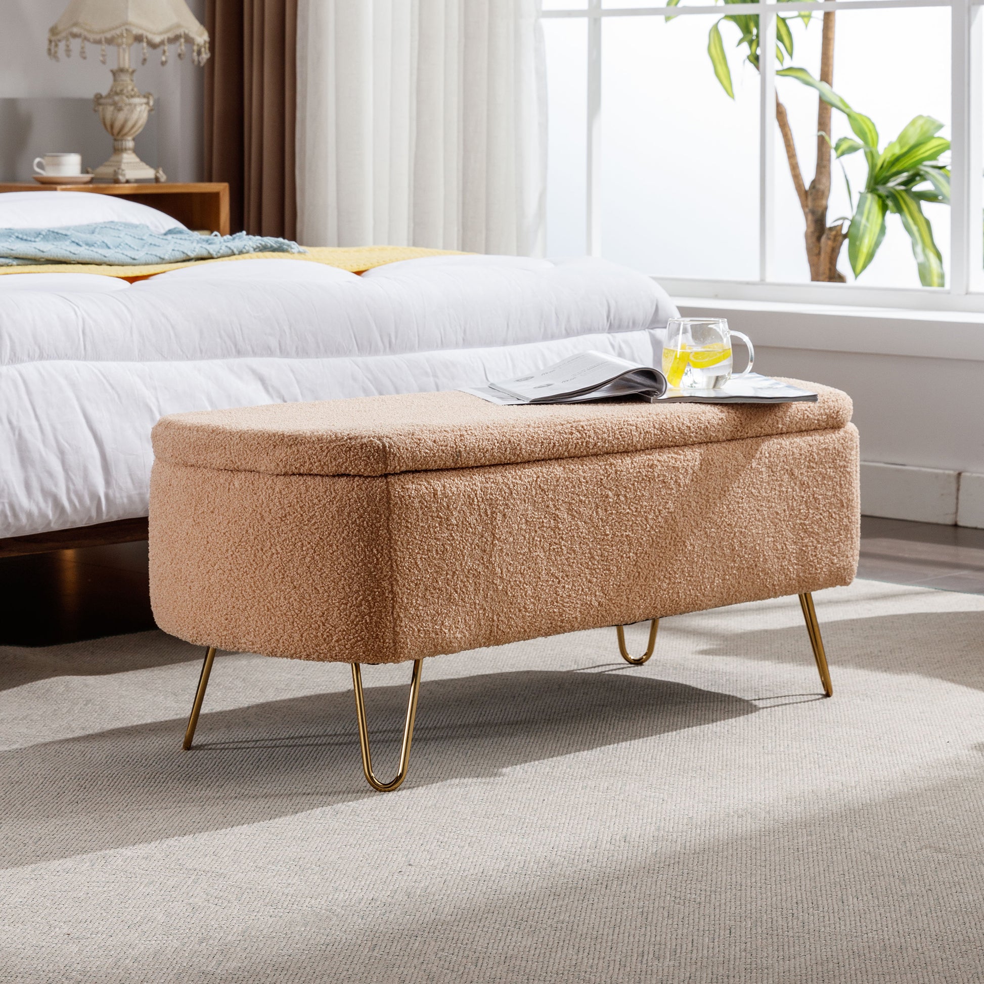 Tan boucle storage ottoman with gold legs perfect for bedroom storage