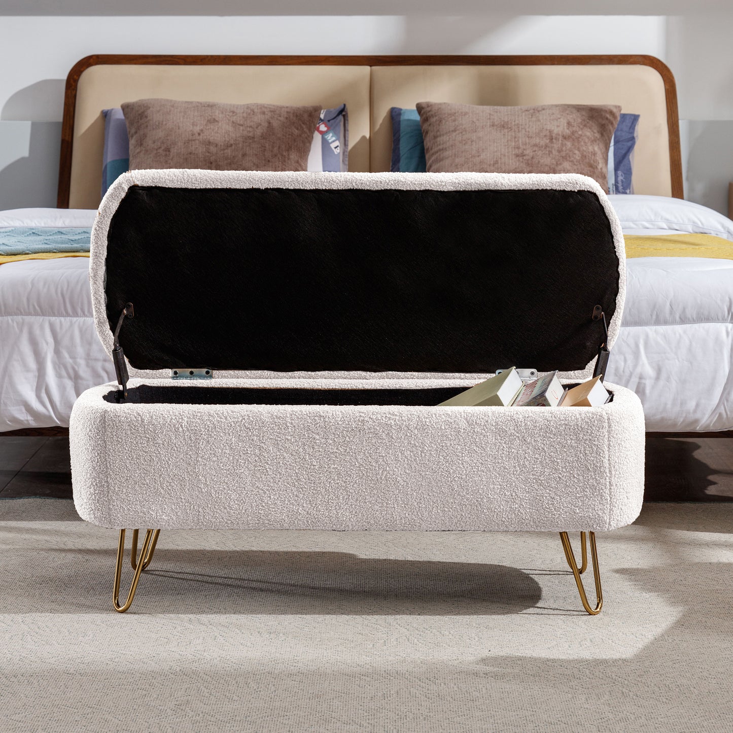 Cream boucle storage ottoman with gold hairpin legs open to reveal books