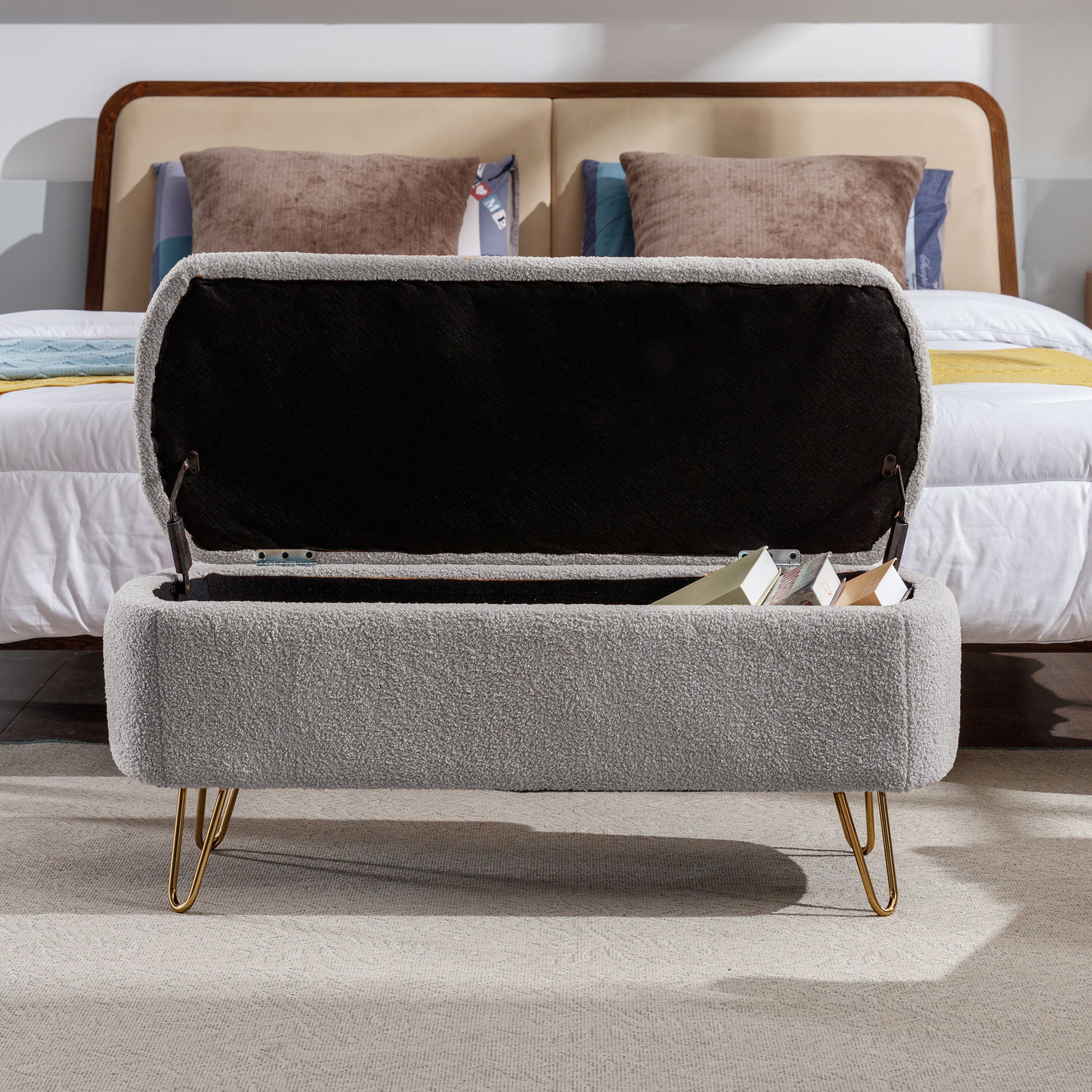 Grey boucle storage ottoman with open lid revealing books and gold hairpin legs