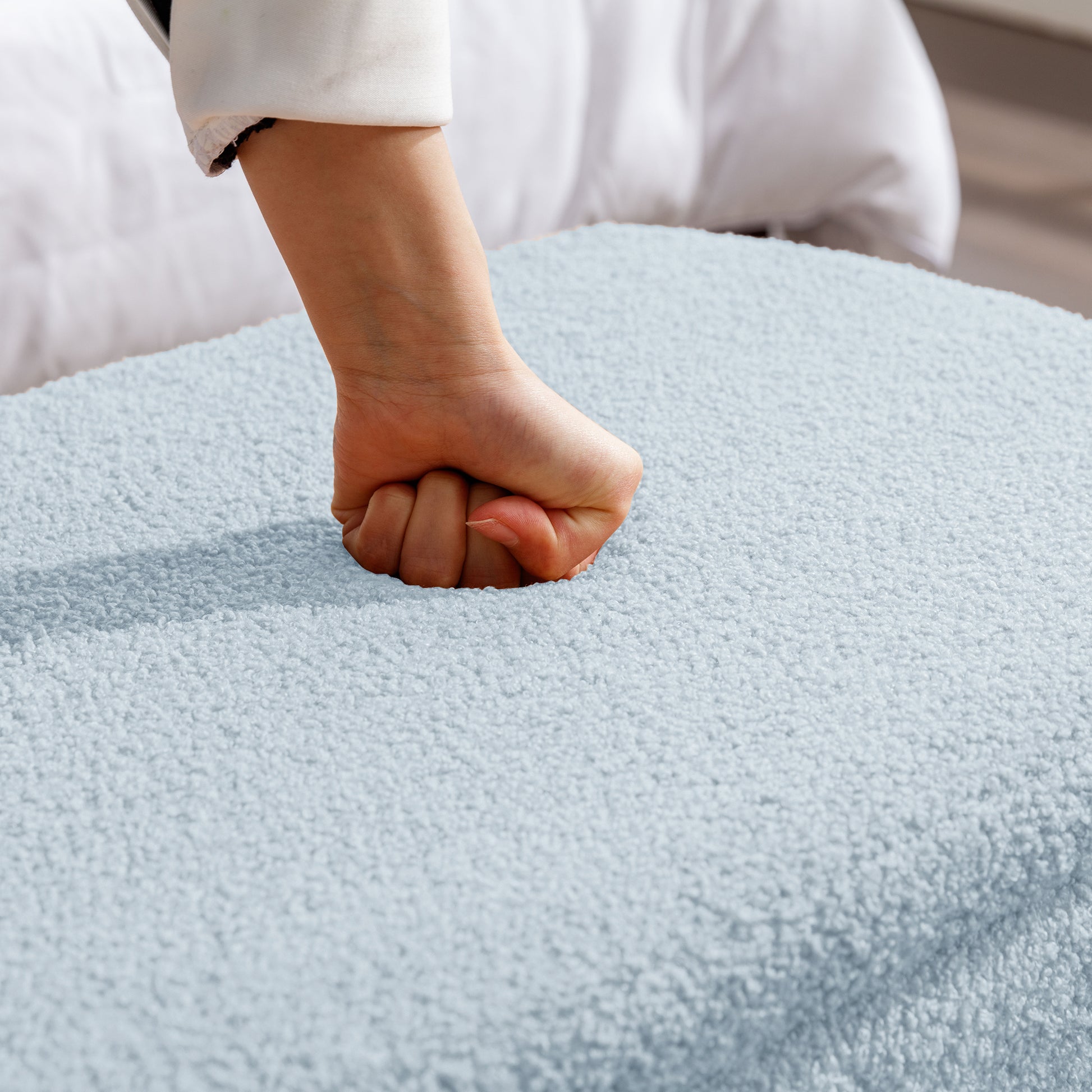 Hand pressing into plush light blue throw pillow for comfort
