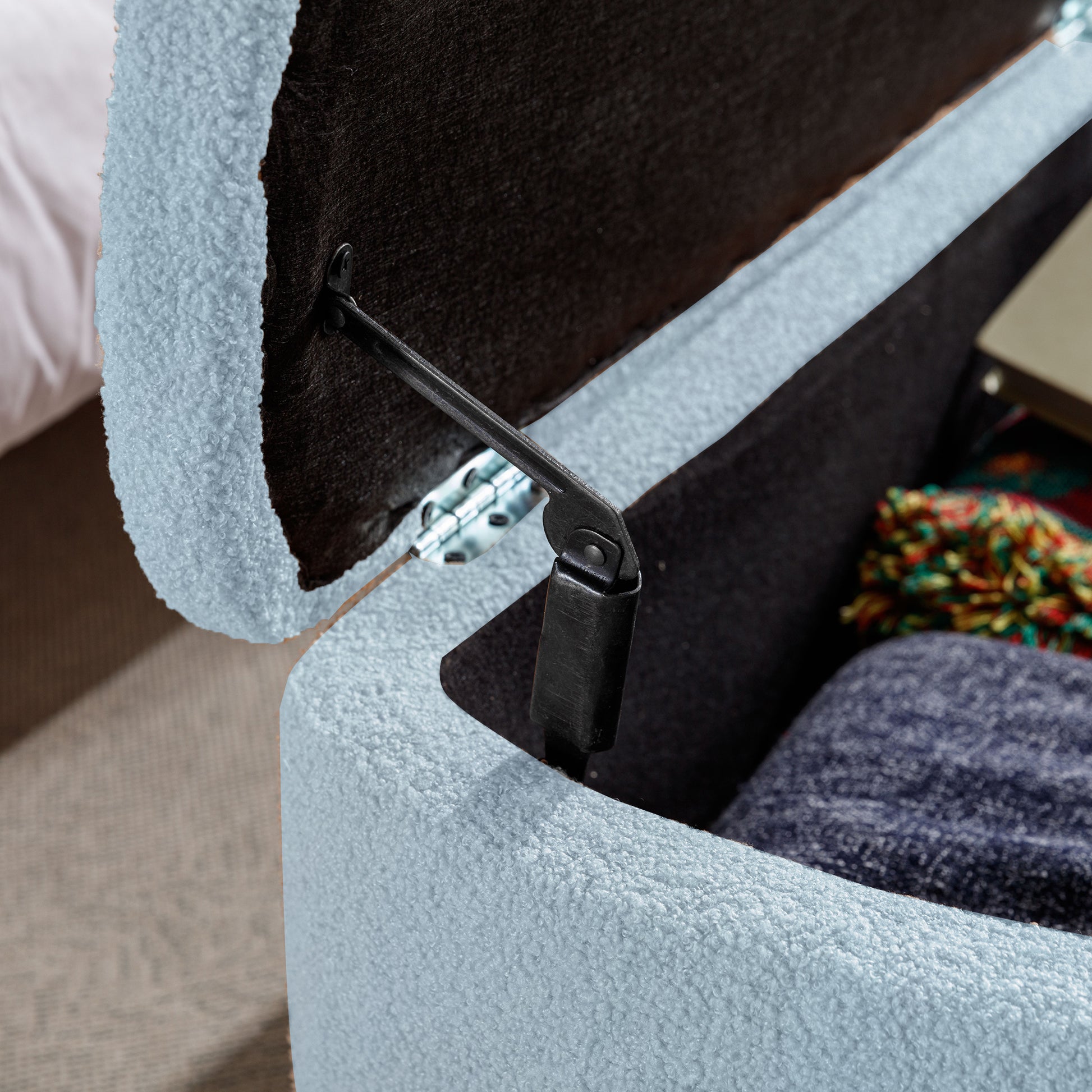 Light blue boucle storage ottoman with dark grey interior and metal hinge