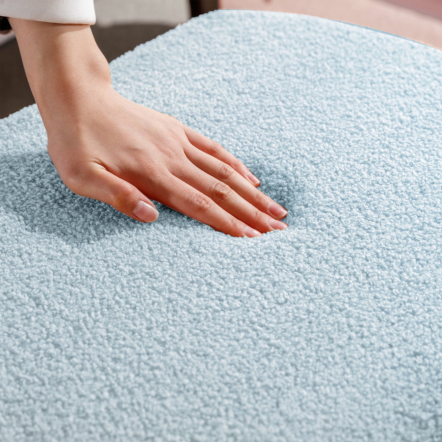 Light blue teddy fleece fabric showing its plush texture with a hand pressing down