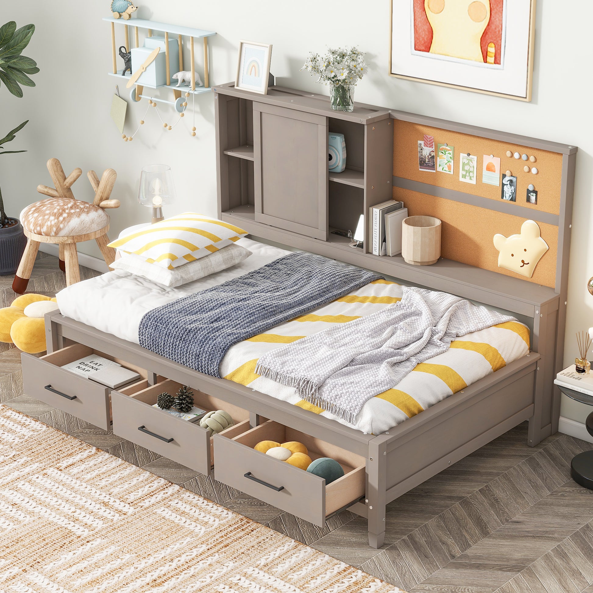 Gray twin bed with three storage drawers and a corkboard headboard