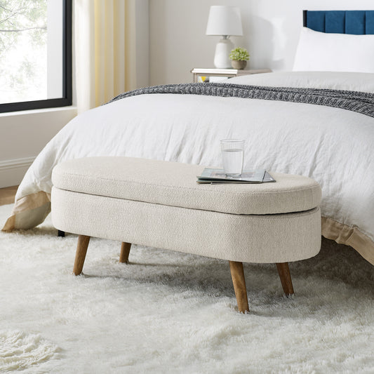 Cream boucle storage ottoman with wooden legs at foot of bed