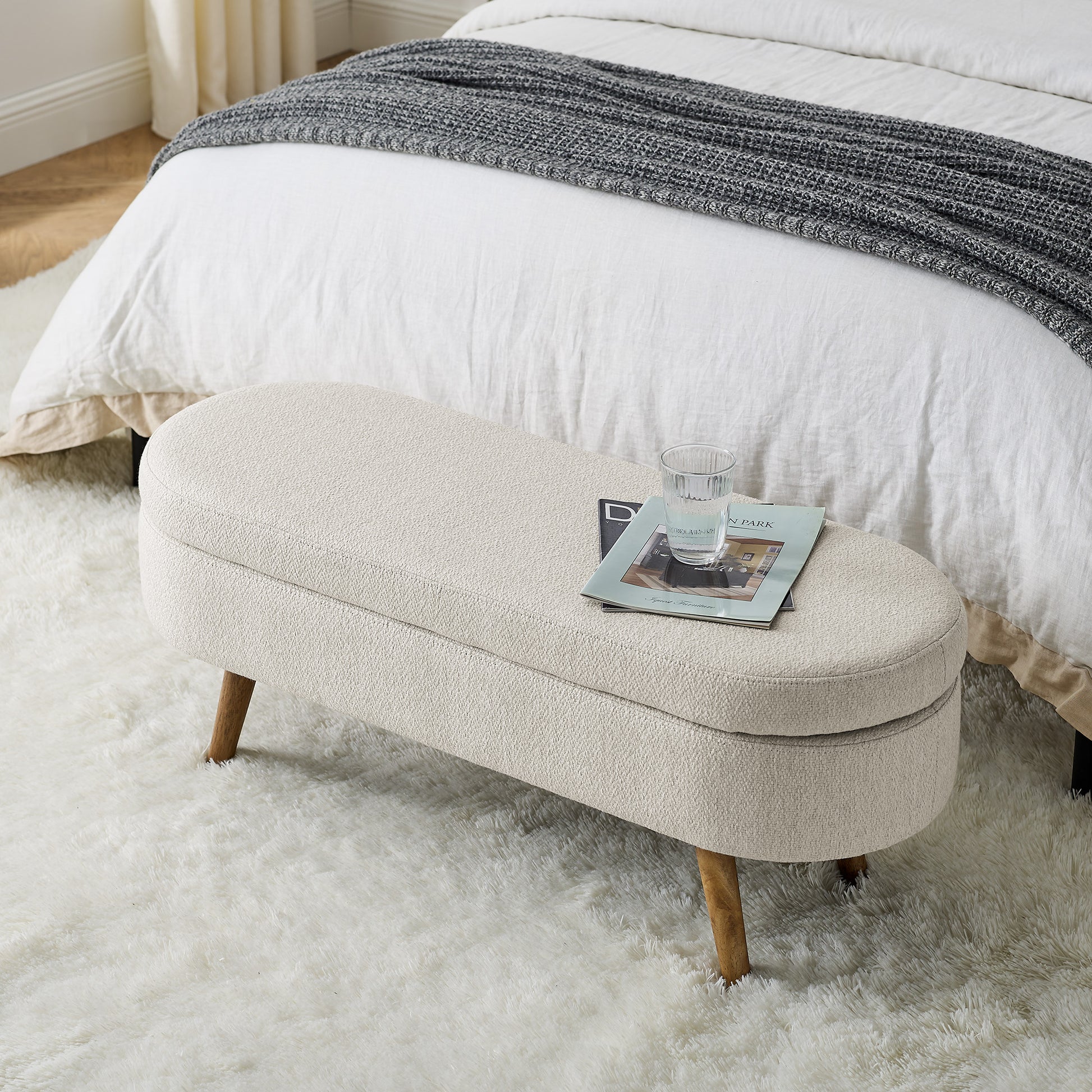 Oval upholstered storage bench in cream boucle fabric with wooden legs