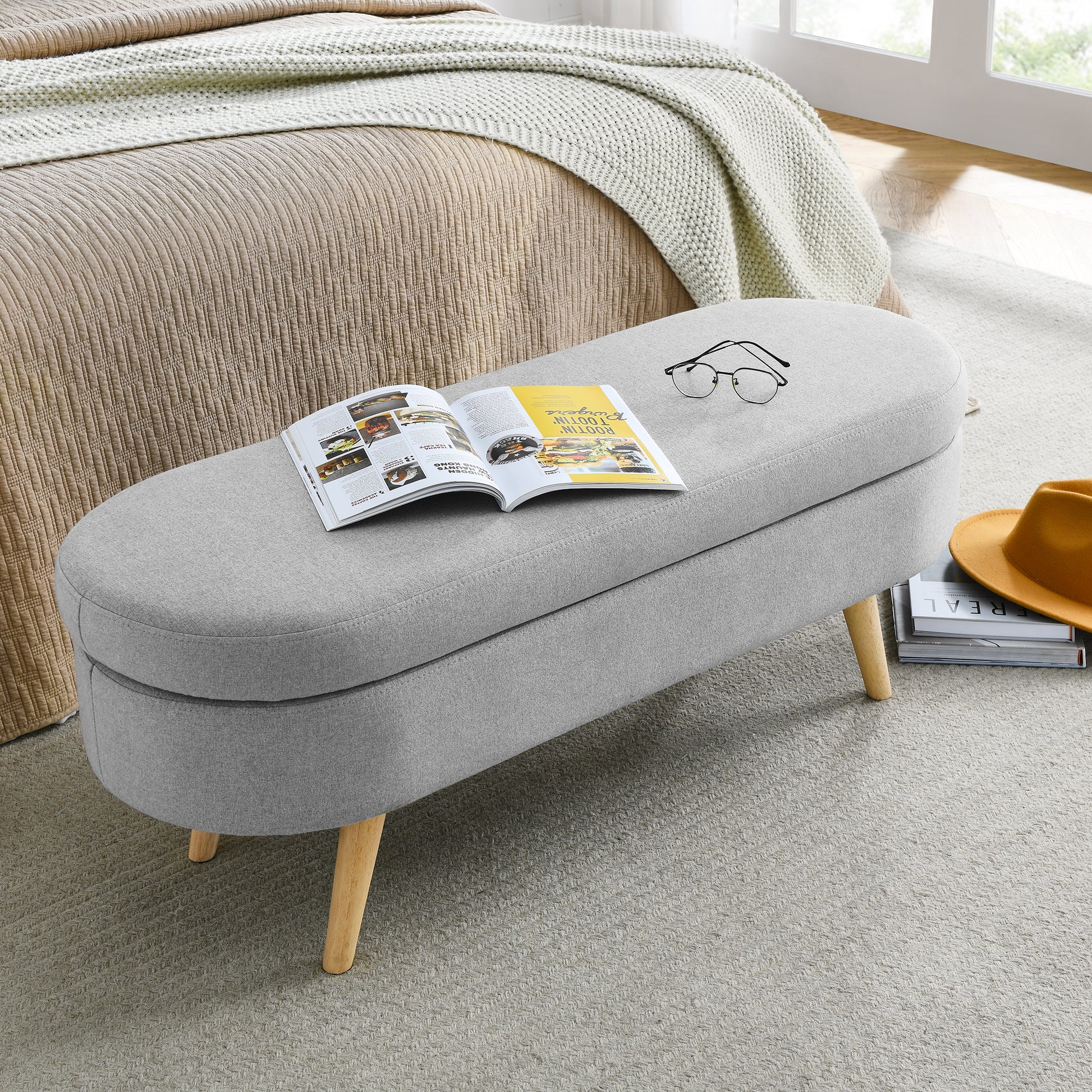 Grey linen storage bench with wooden legs and open magazine