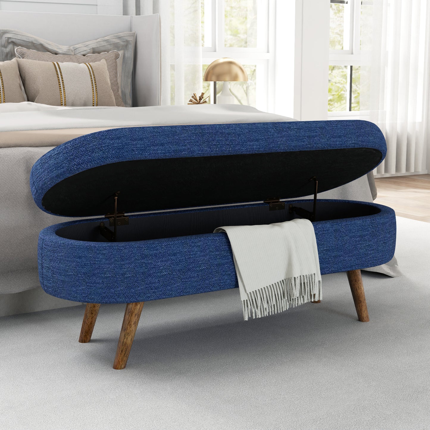 Blue fabric storage bench with tapered wooden legs and open lid revealing white blanket