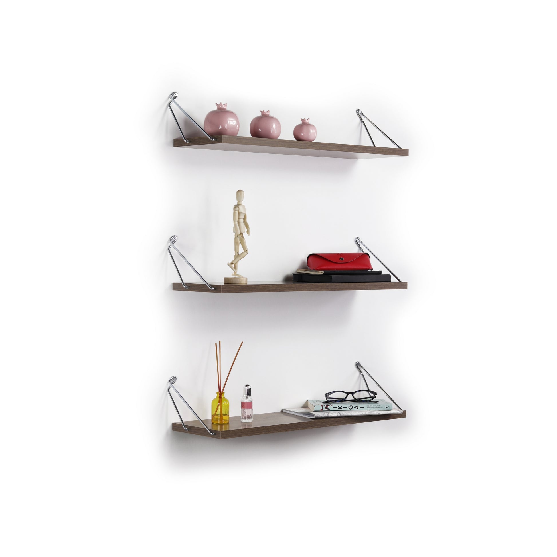 Three pink ceramic pomegranate decorative objects on a brown floating shelf
