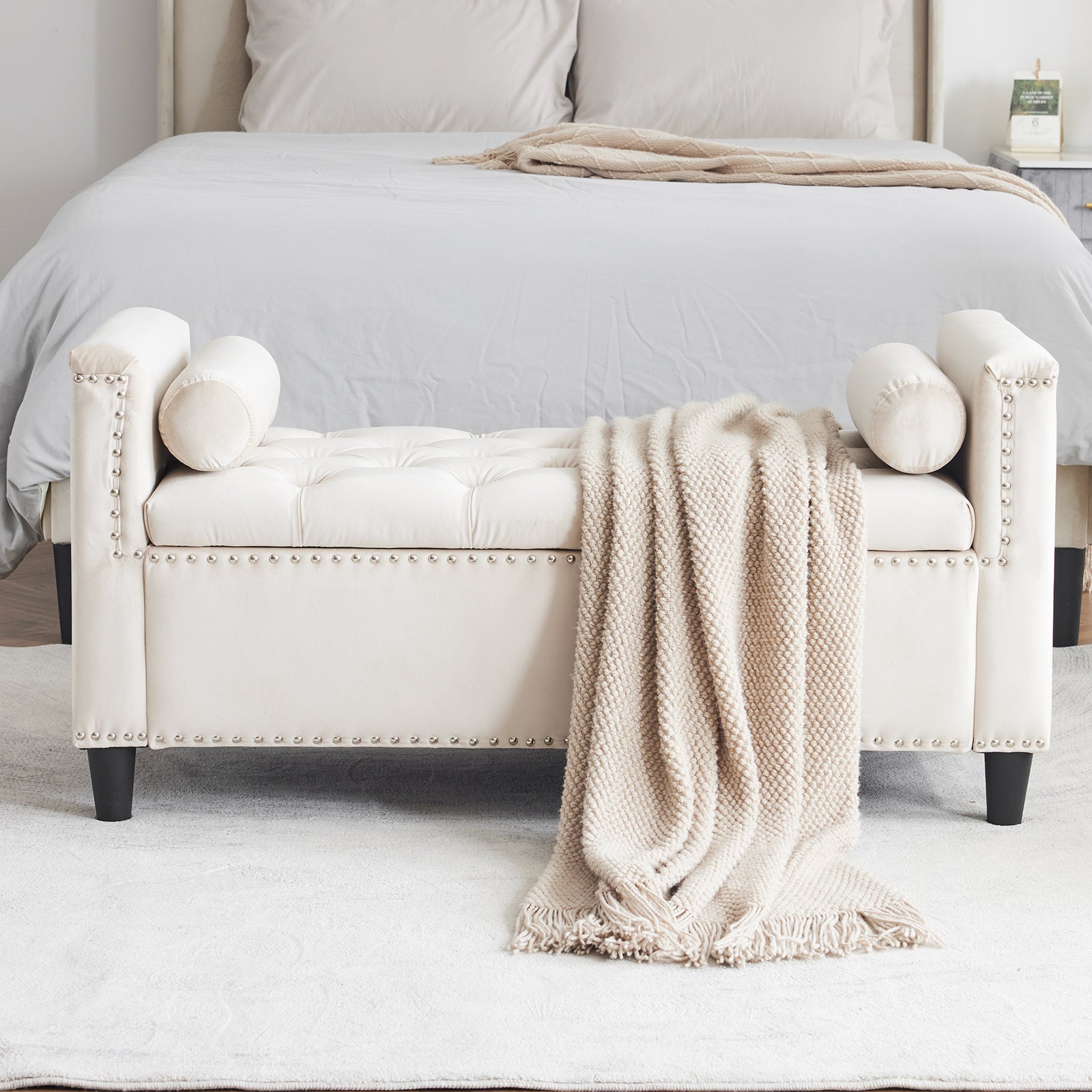 Cream upholstered bench with tufted seat and silver nailhead trim