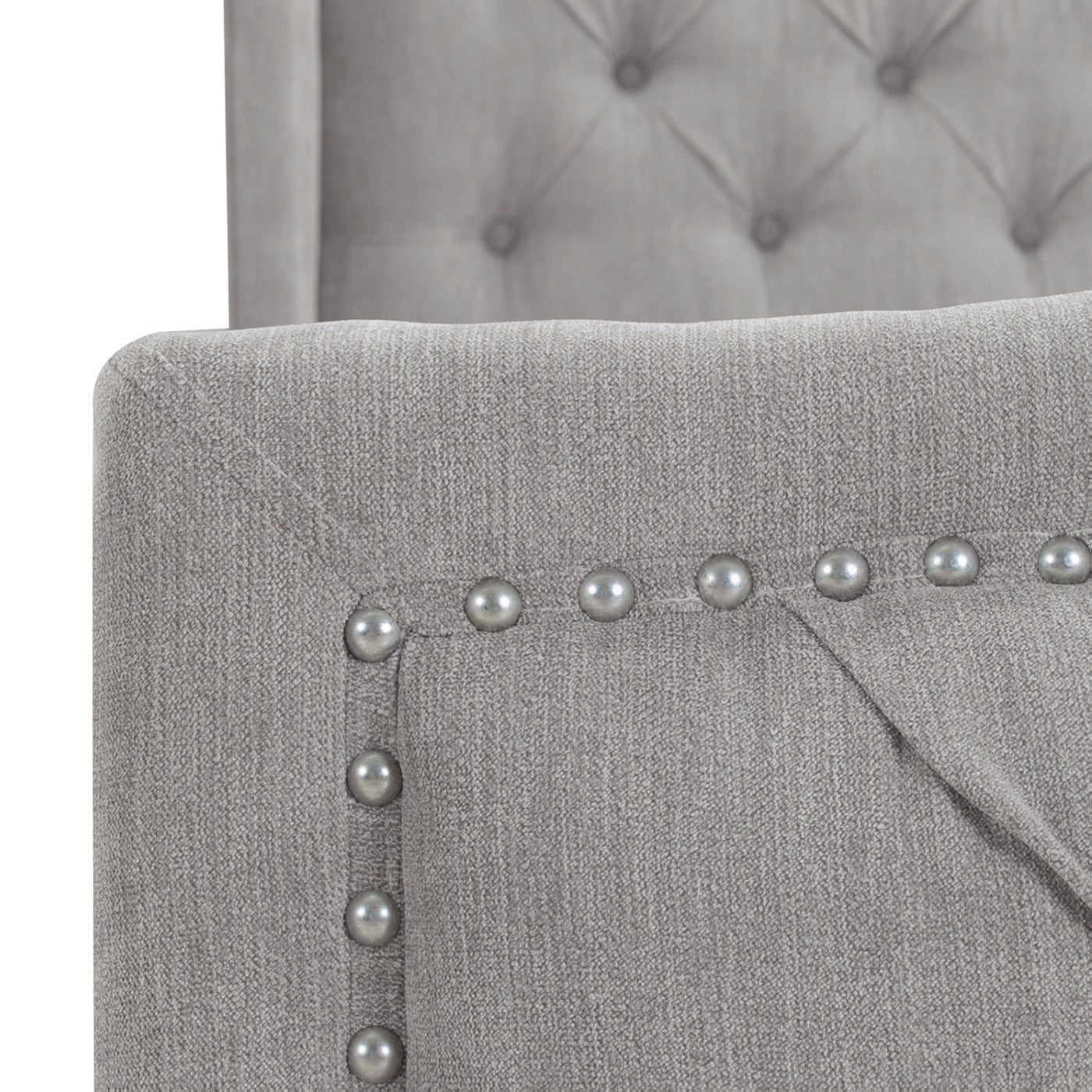 Closeup of grey upholstered chair arm with decorative silver nailhead trim