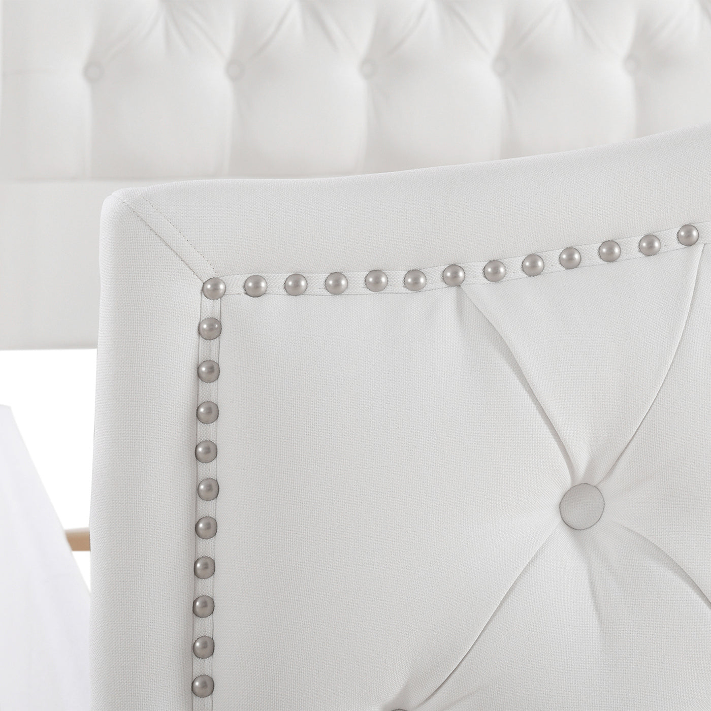 Closeup of white upholstered headboard with nailhead trim detail
