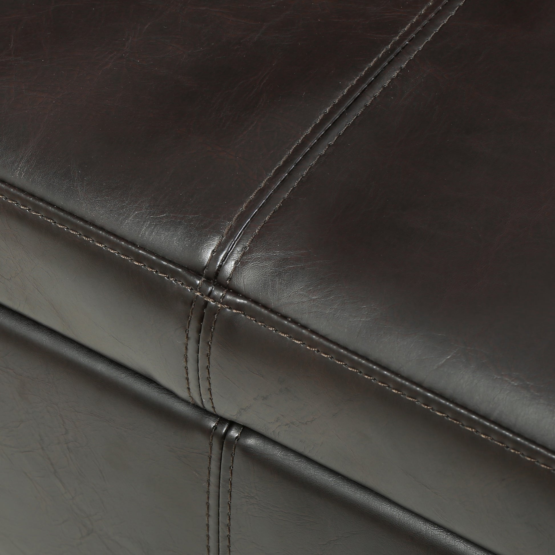 Closeup of dark brown faux leather upholstery with visible stitching