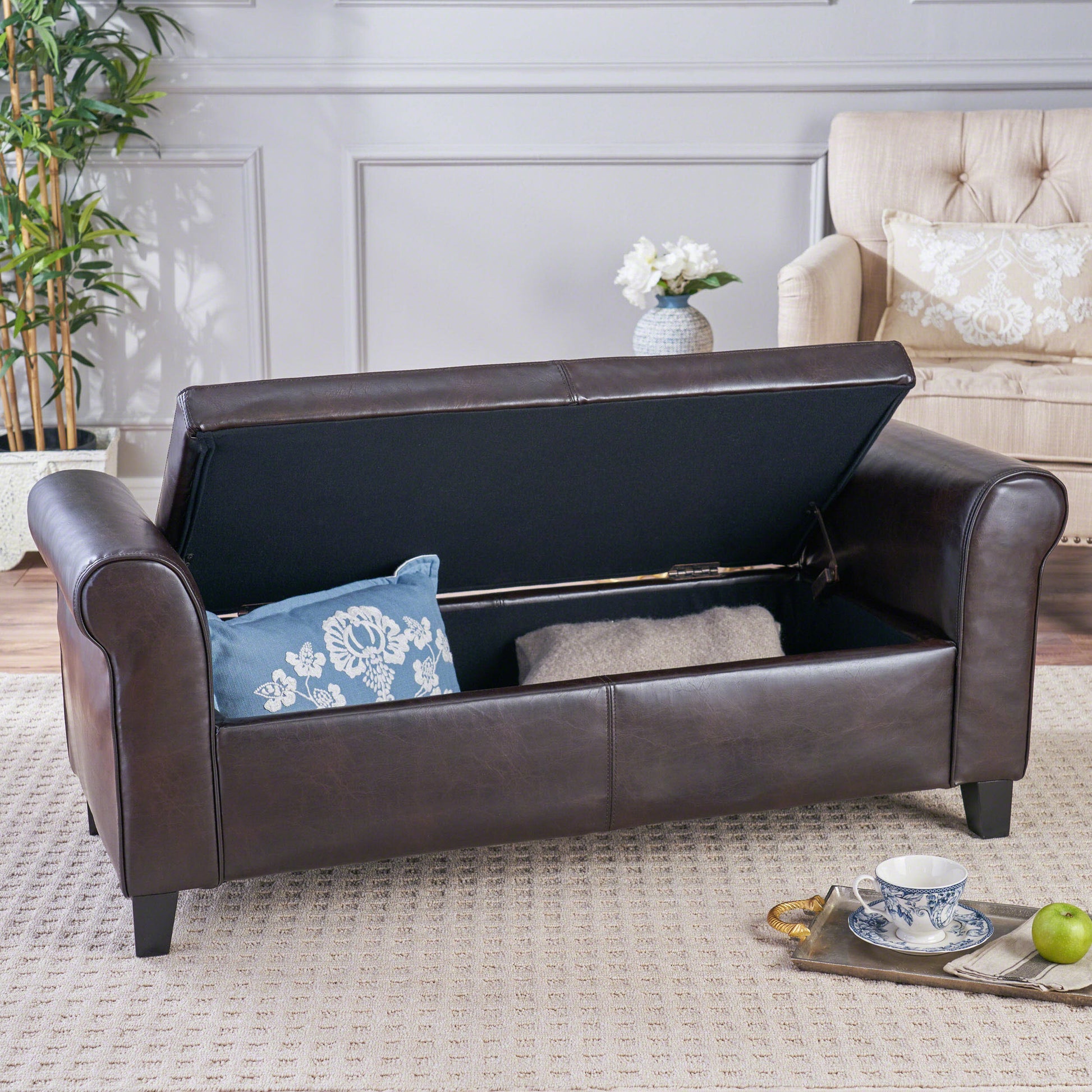 Dark brown faux leather storage bench with carved arms and tufted details