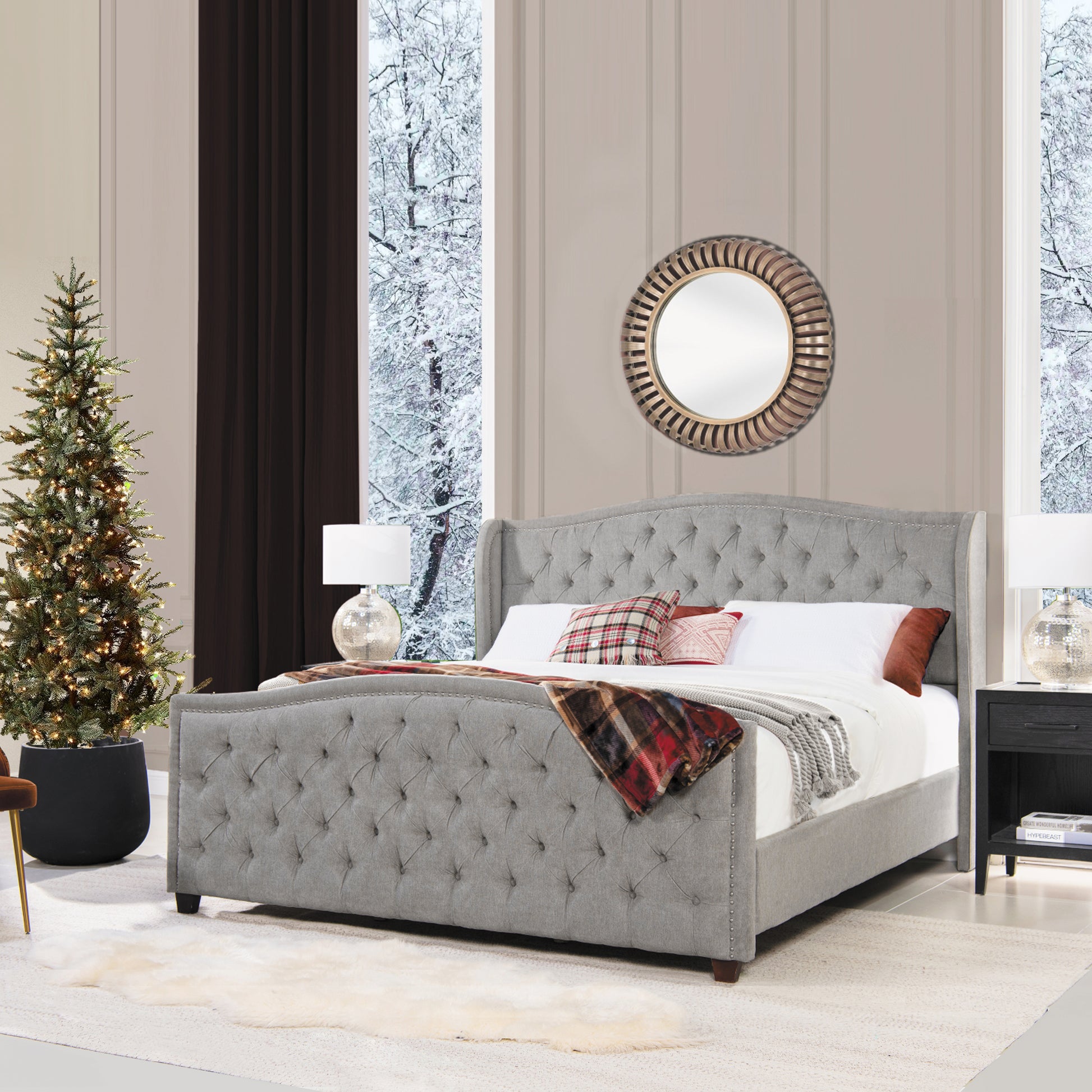 Grey tufted wingback bed with studded trim and plaid blanket