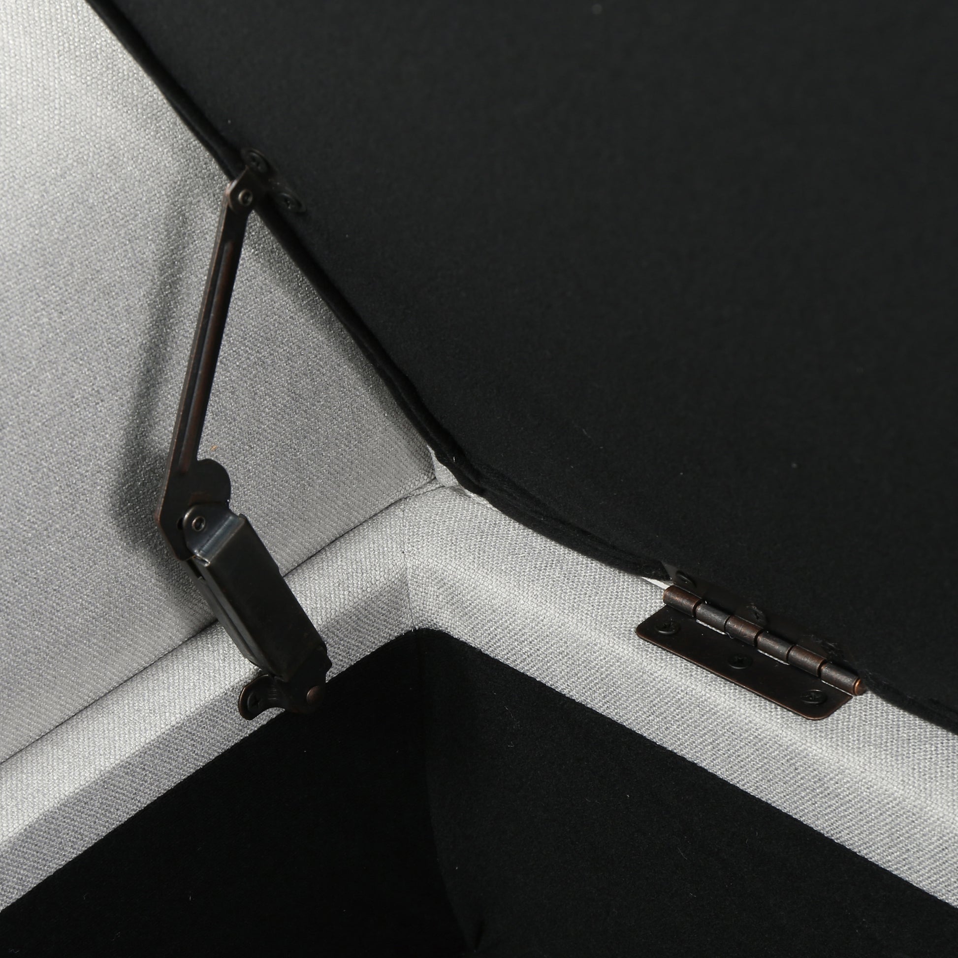 Closeup of a gray upholstered ottoman hinge mechanism