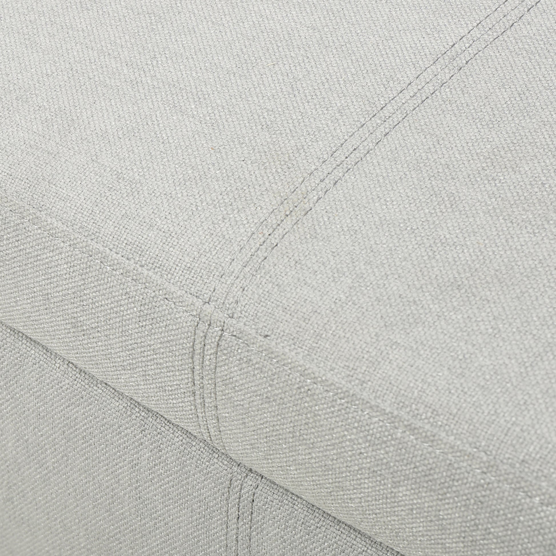 Closeup of light grey textured fabric with subtle stitching details