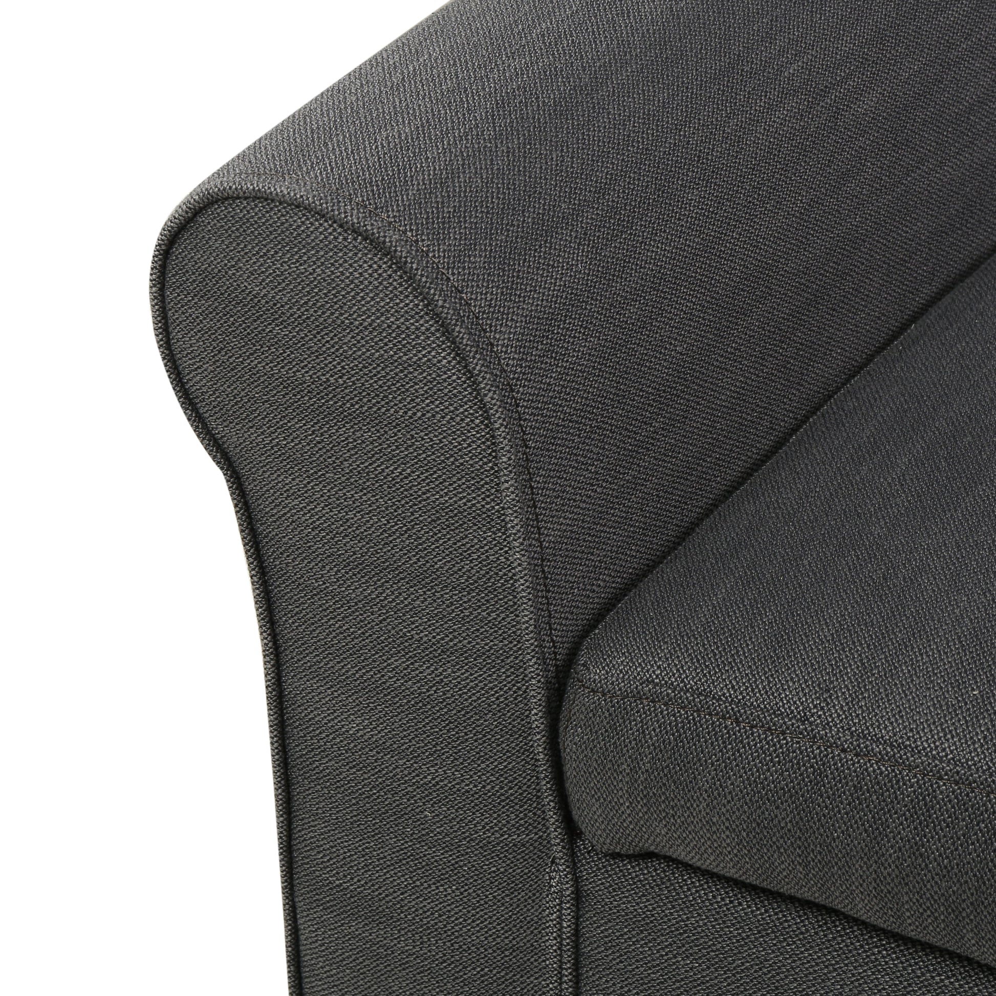 Closeup of a charcoal gray upholstered sofa armrest with textured fabric