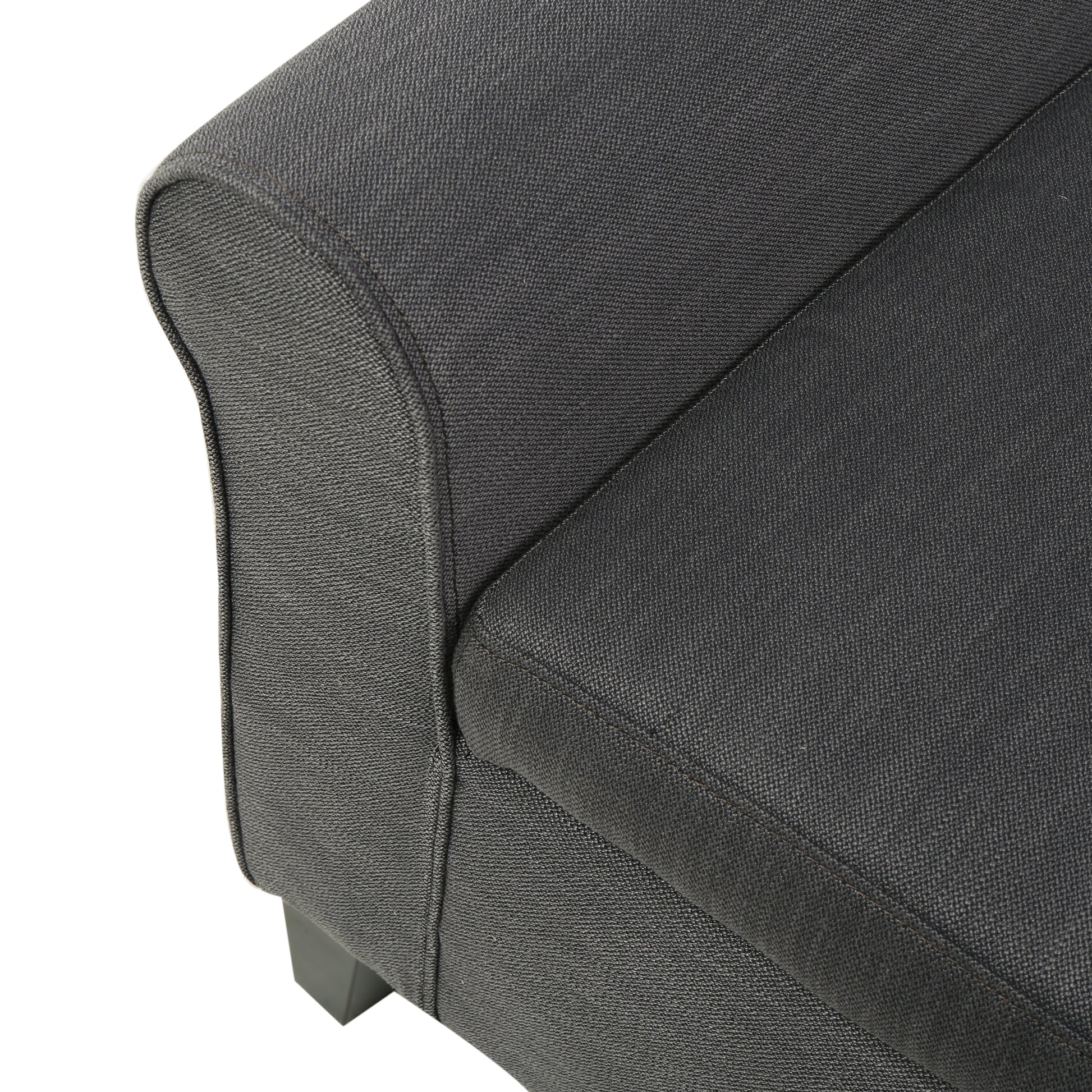 Closeup of textured dark gray fabric sofa armrest with stitching detail