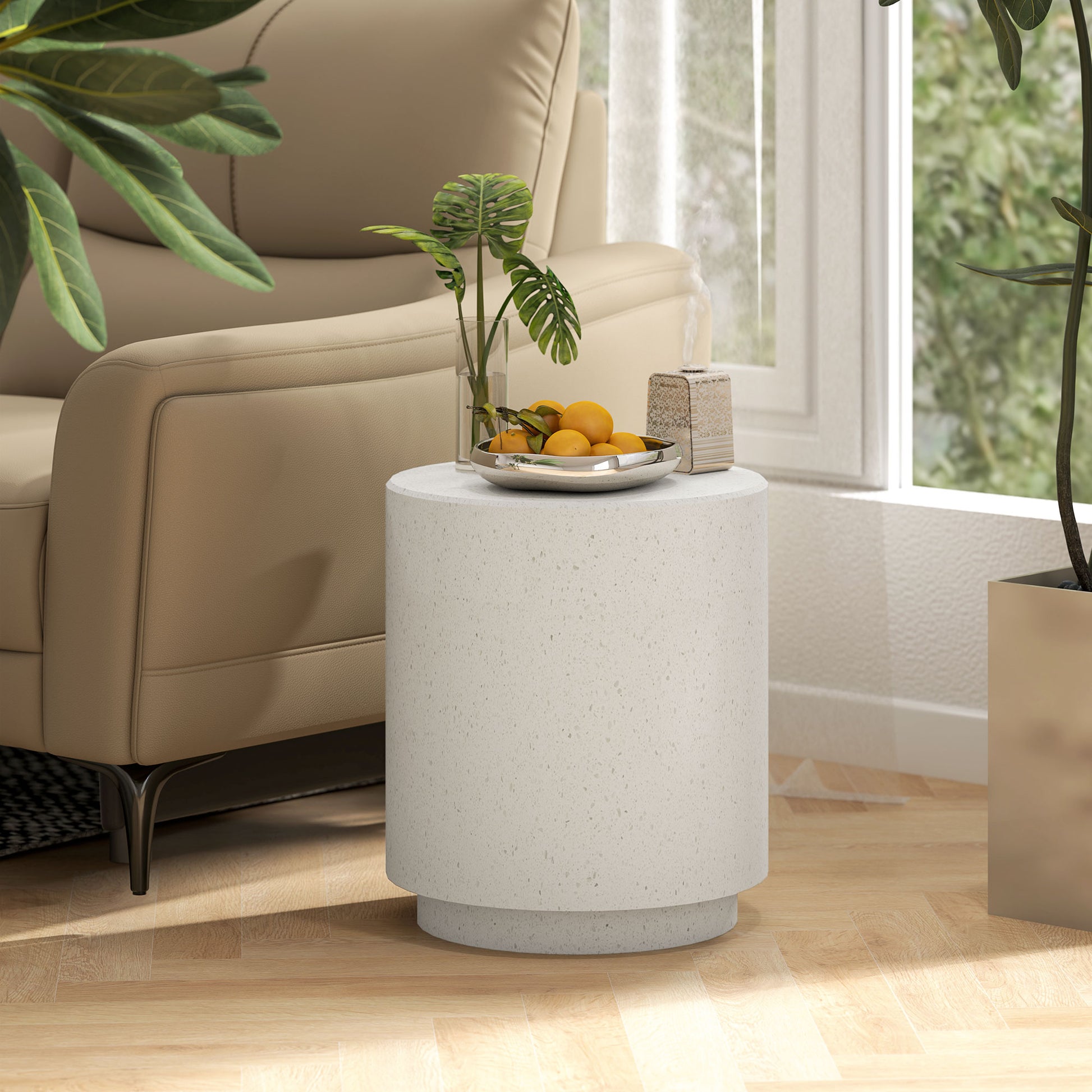 Round speckled white terrazzo side table with chrome bowl of oranges