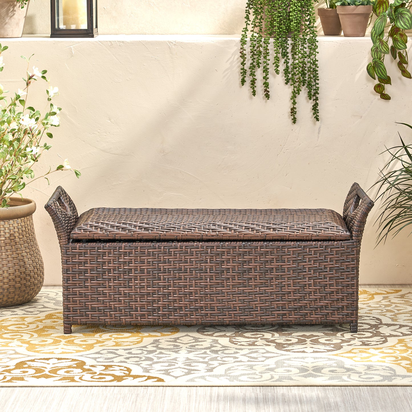 Brown wicker storage bench with decorative weaving and side handles for patio use