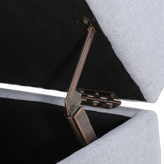 Closeup of a grey linen storage ottomans open lid showing antique bronze hinges
