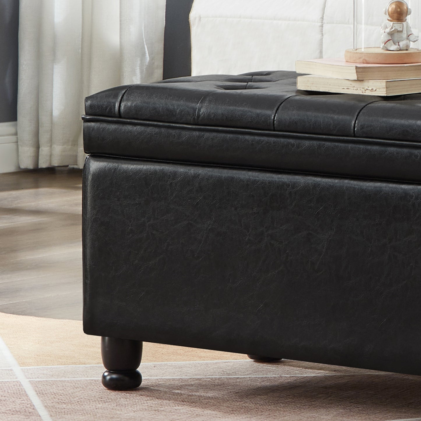 Black faux leather storage ottoman with tufted top and dark wooden legs