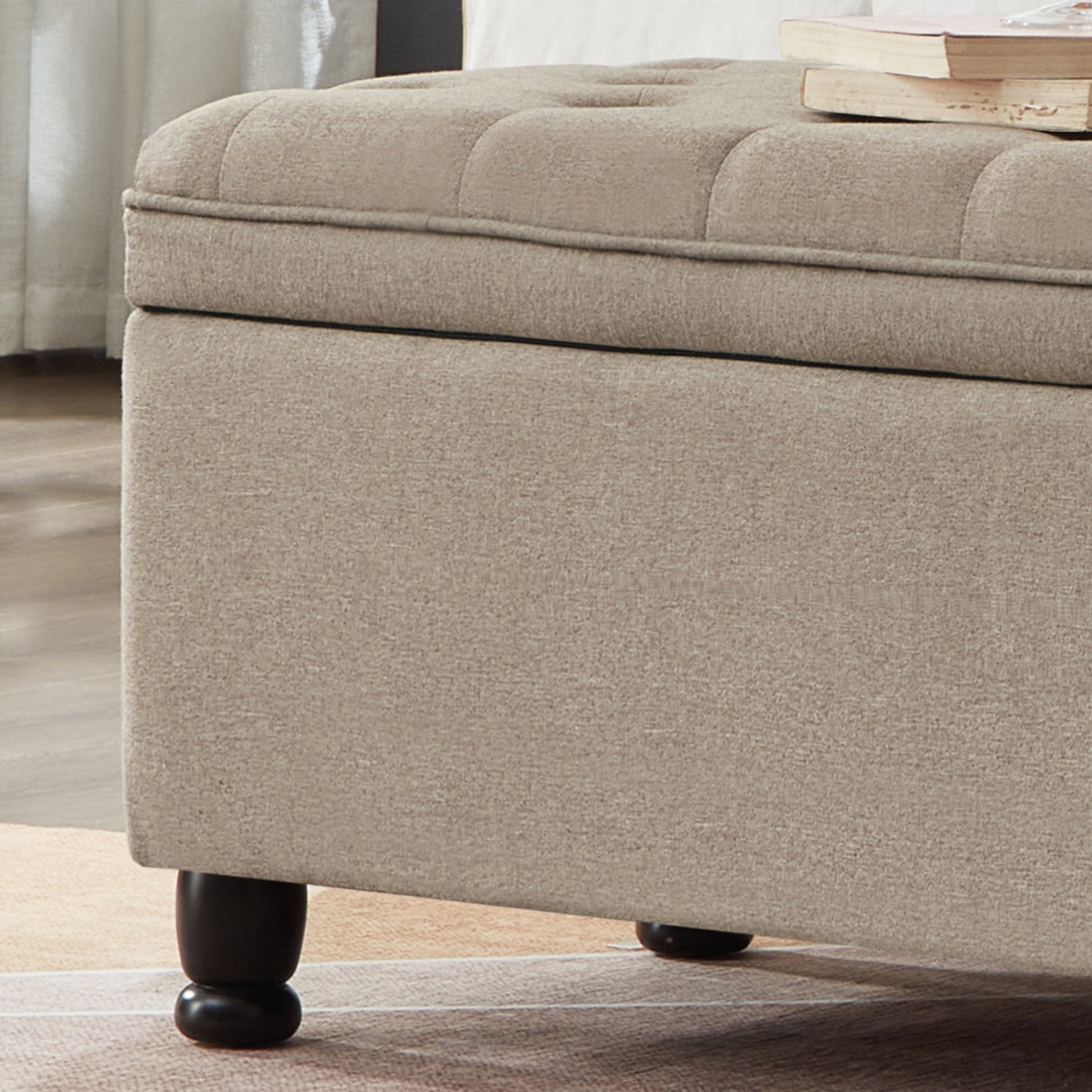 Tufted beige storage ottoman with dark wood legs and a linenblend fabric cover