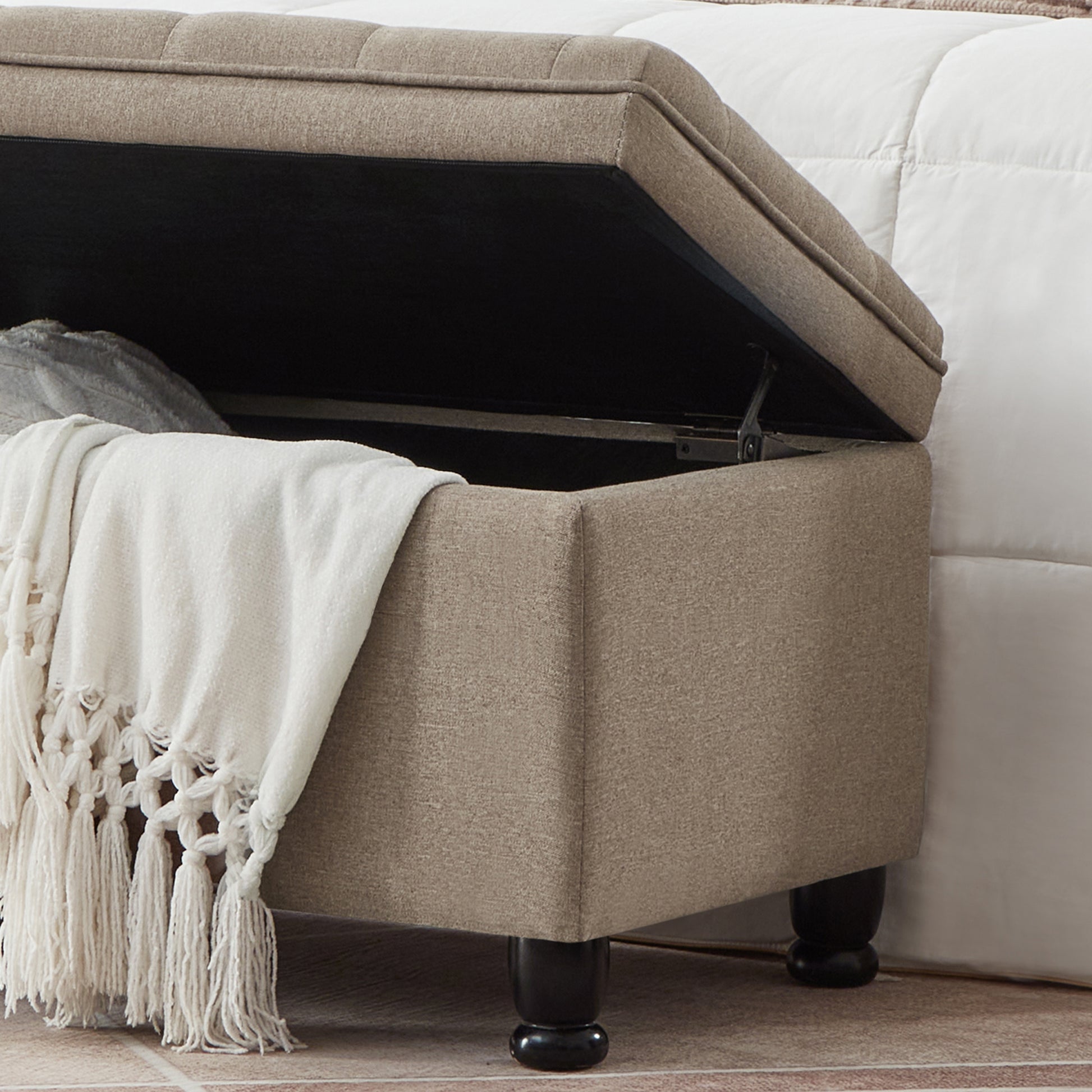 Tufted beige storage ottoman with dark wood legs and open lid