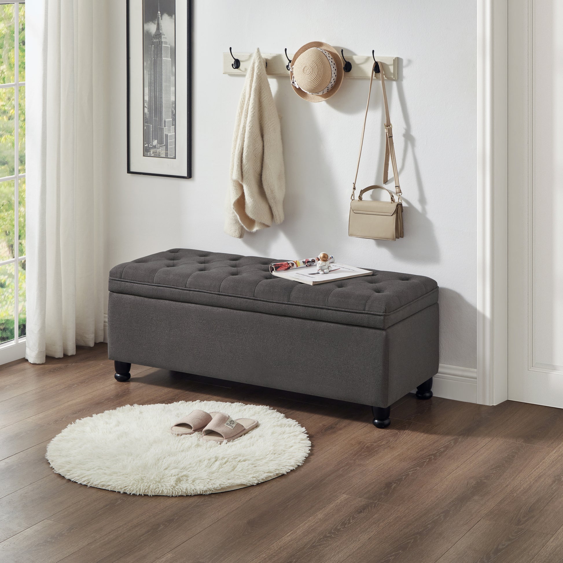 Tufted dark grey fabric storage ottoman with wooden legs and a quilted lid