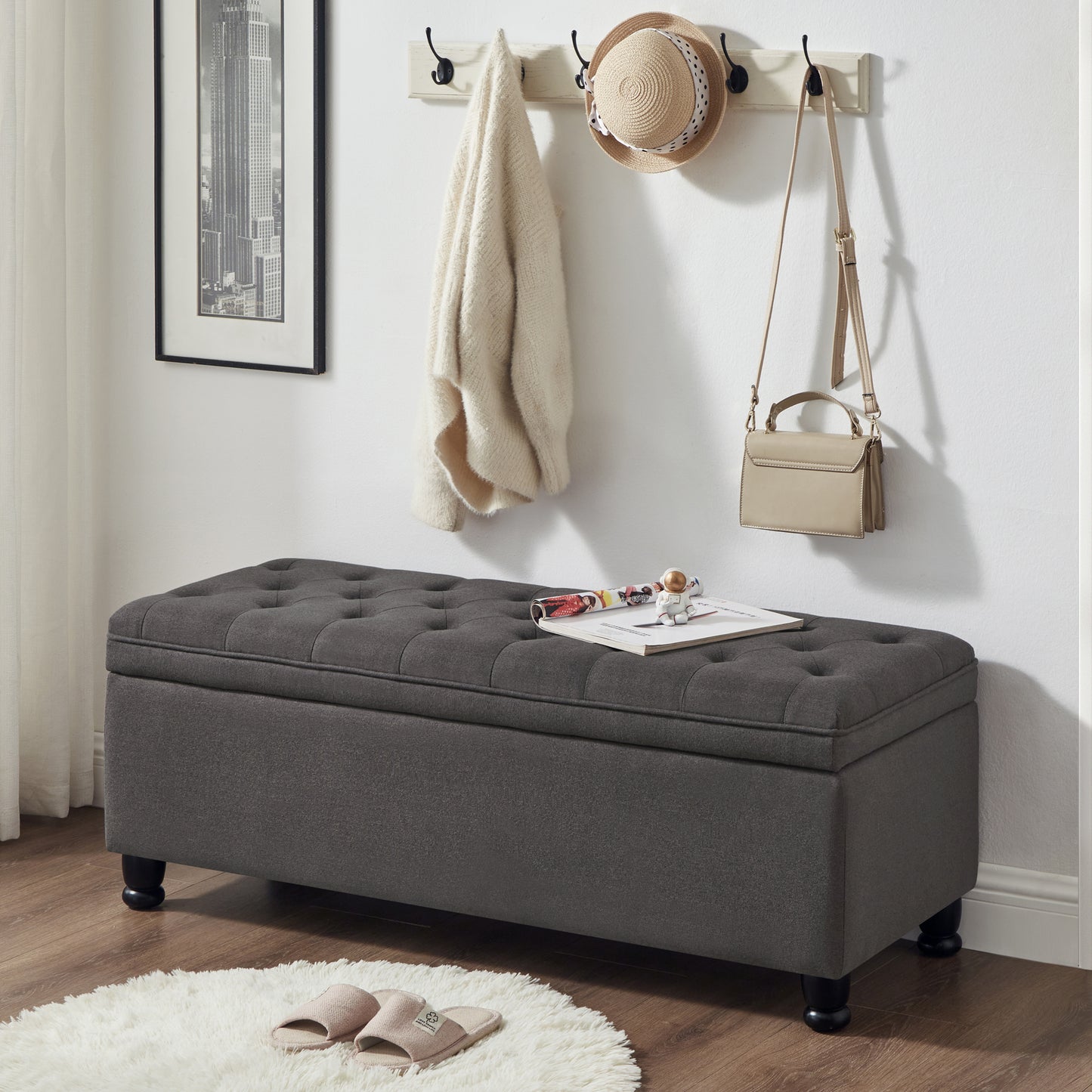 Dark gray tufted storage ottoman with upholstered lid and black wooden legs