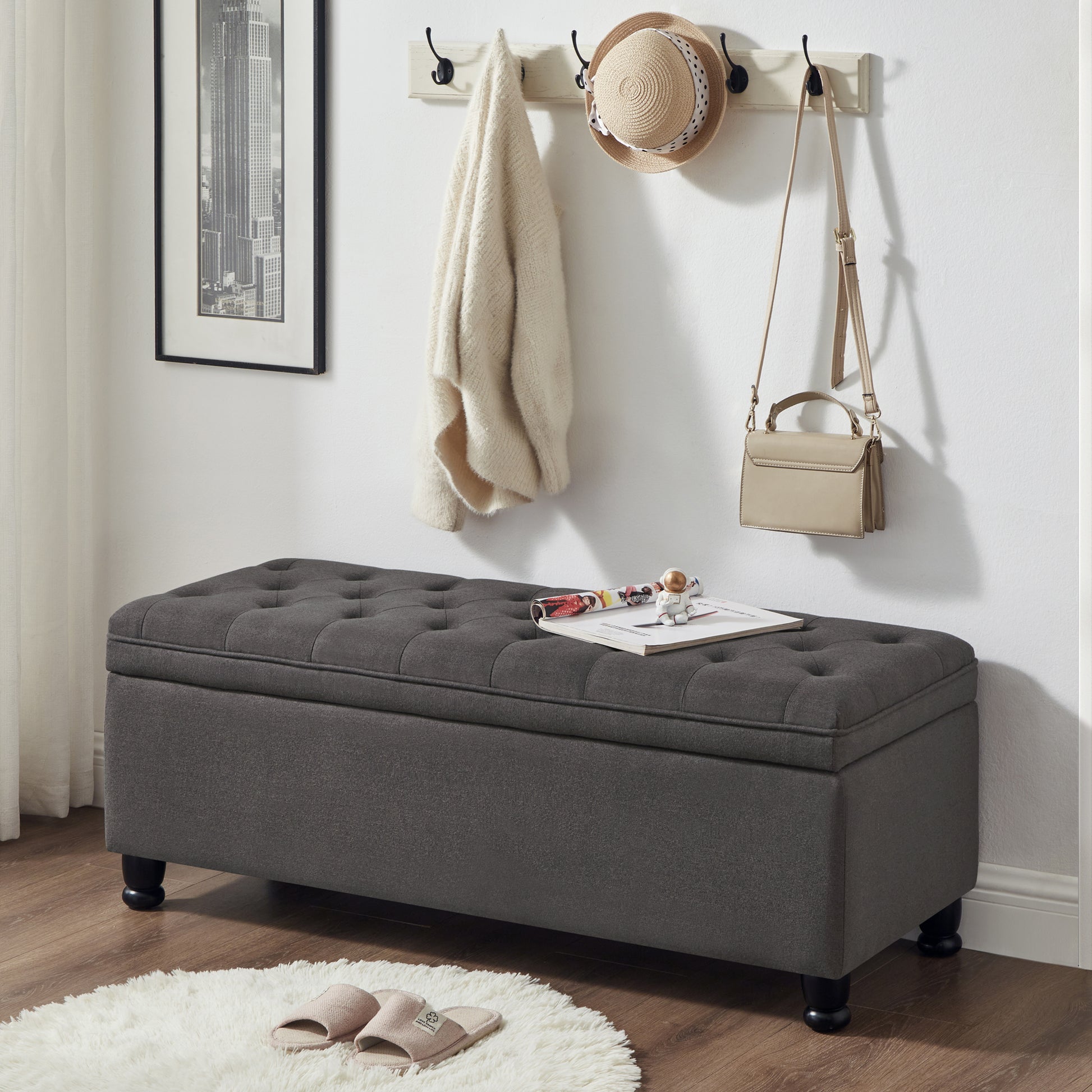 Dark gray tufted storage ottoman with upholstered lid and black wooden legs